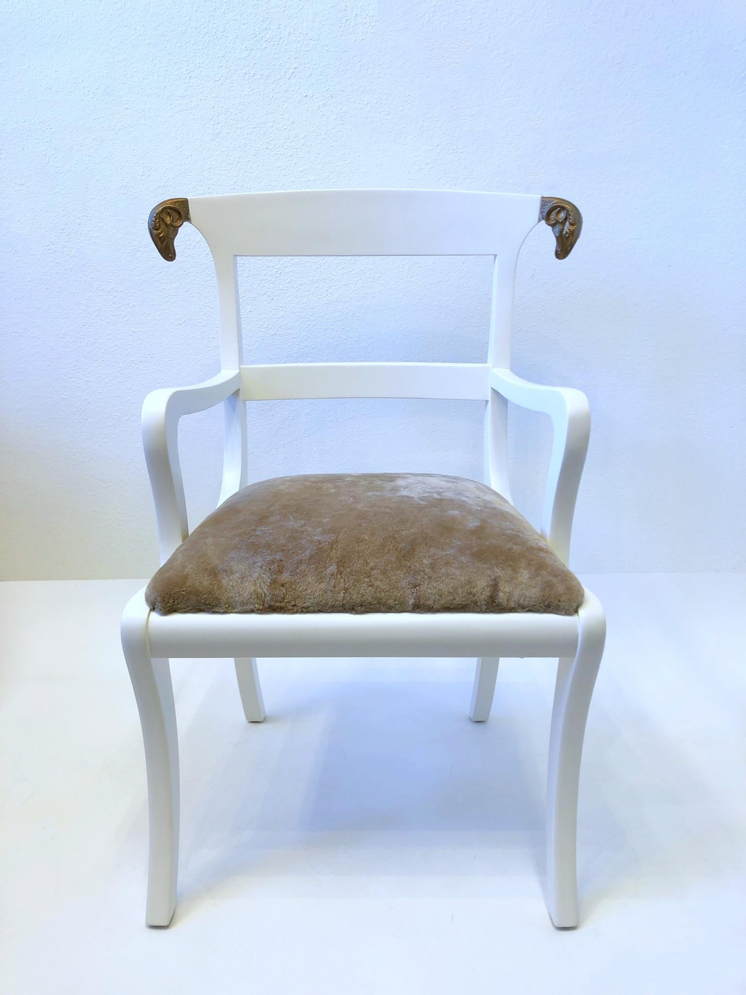 1980’s white lacquered armchair with gold rams head details, designed by Colombian designer Enrique Garcel. 
The seat is newly recovered with a soft lite mocha shearling.
Measurements: 28” Wide, 23.25” Deep, 36.75” High, 20” Seat, 26” Arm.