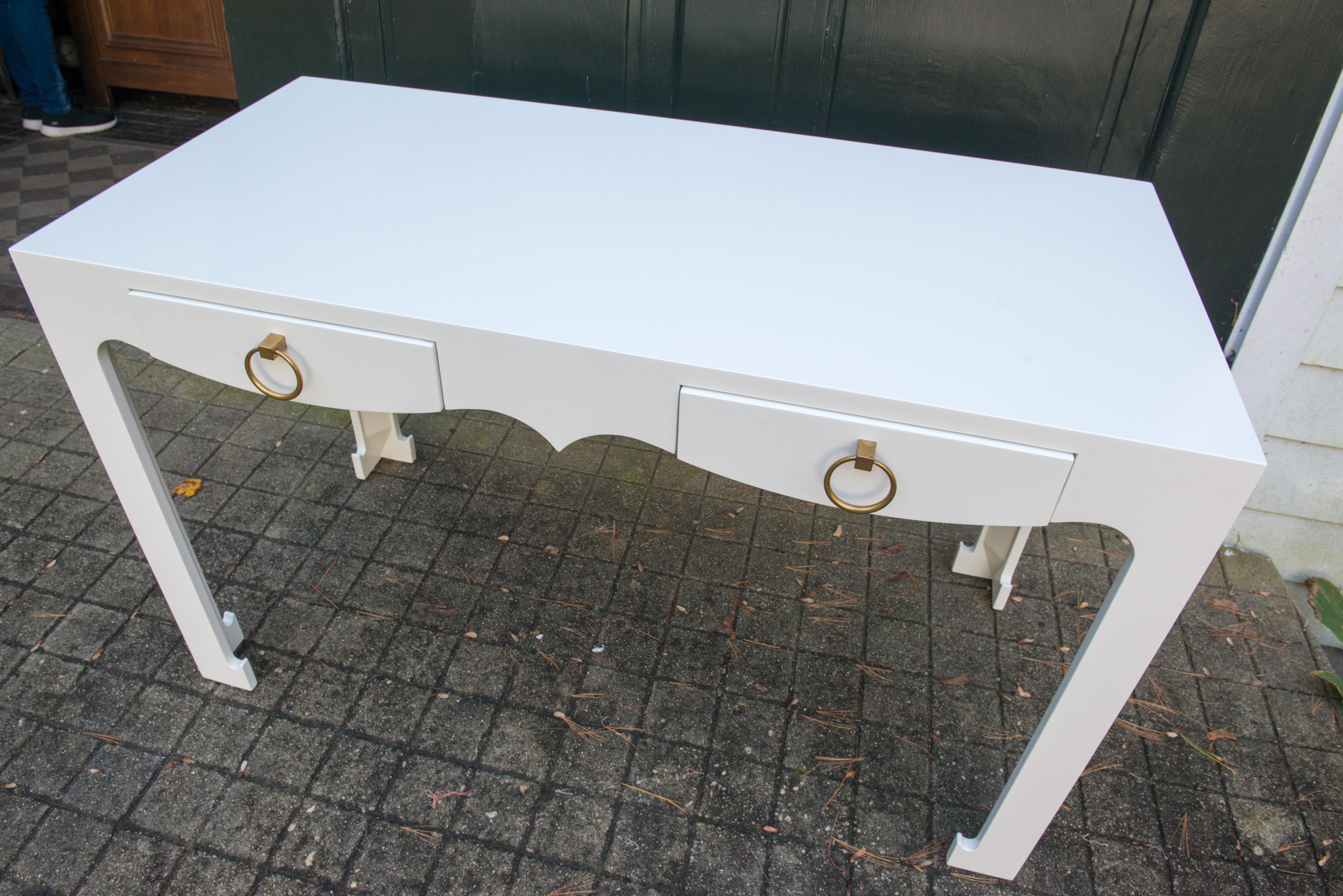White lacquered desk, two drawers with brass ring pulls. Clearance height 23.5. Desk or console finished on all sides.