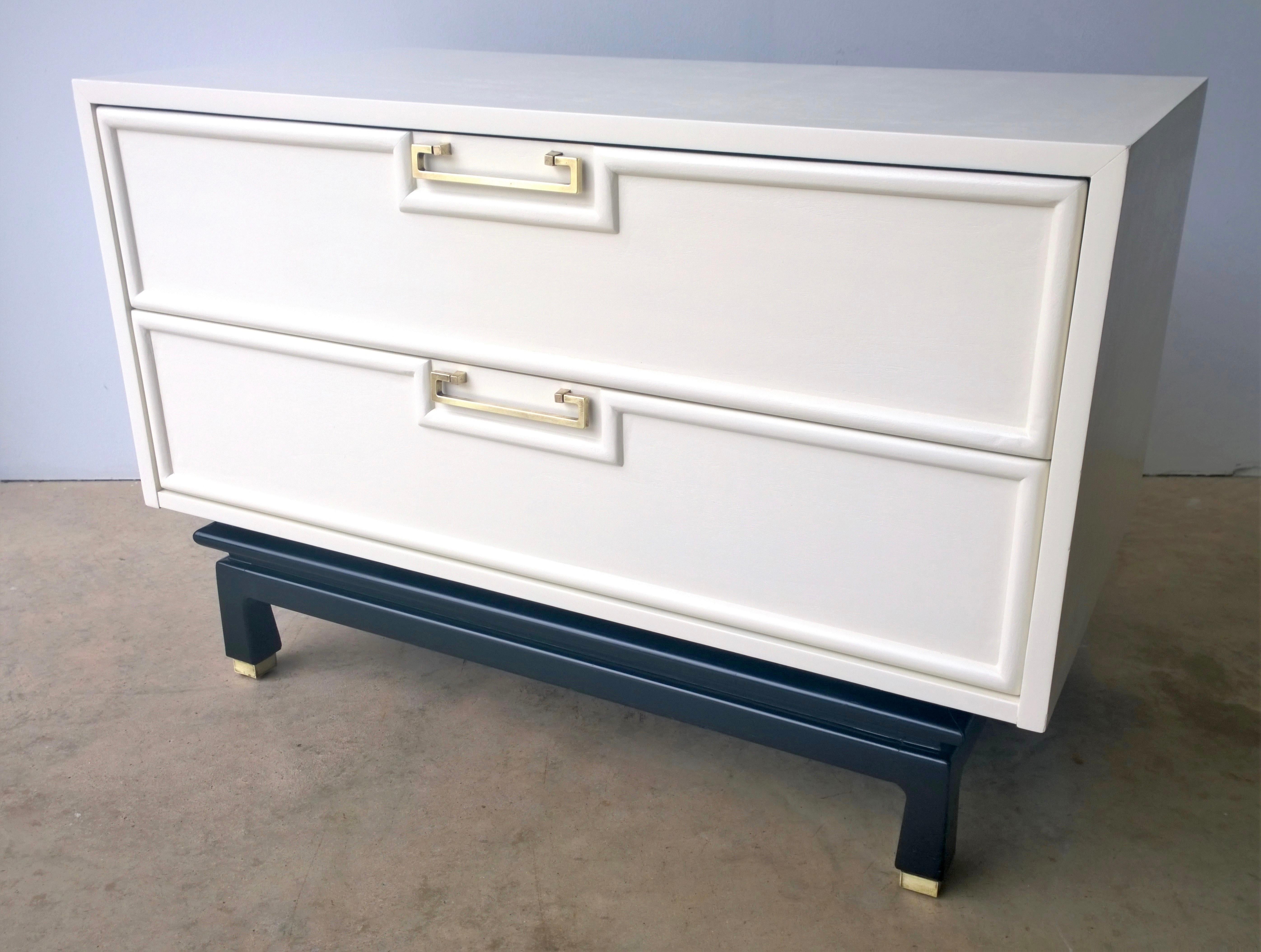 Offered is a signed Mid-Century Modern American of Martinsville Asian / chinoiserie inspired two-drawer bedside table / chest of drawers newly lacquered in a creamy white over mahogany with brass pulls, sabots and black wood base. This piece is