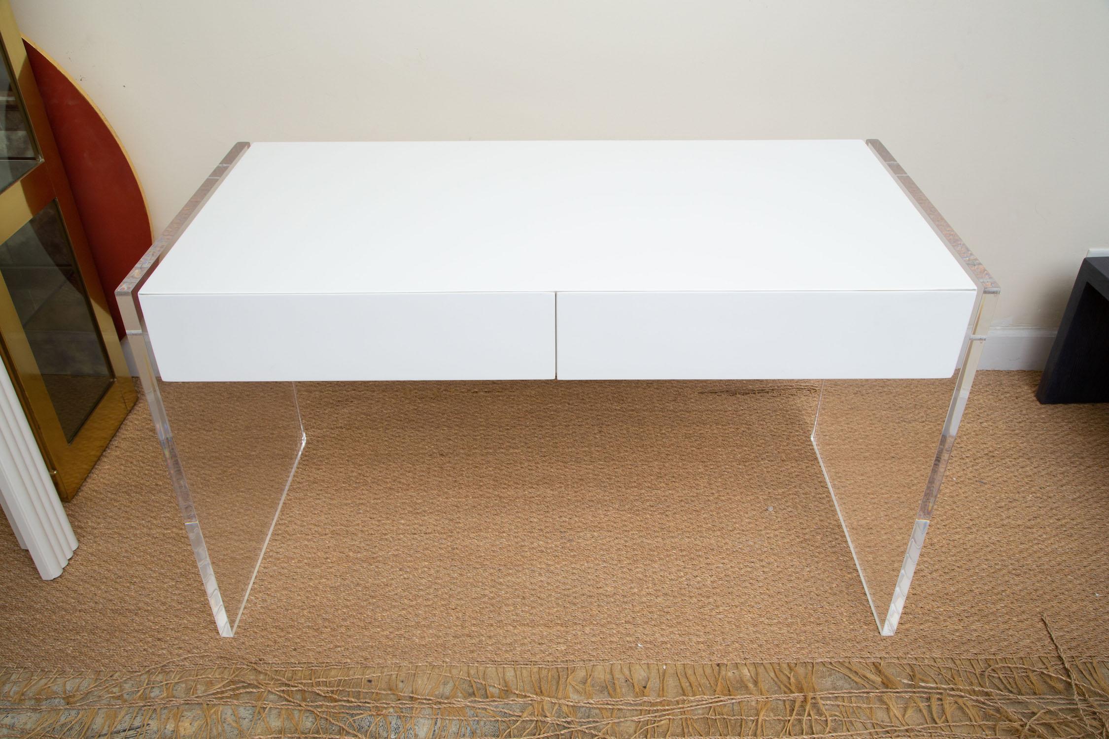 This white lacquered over wood desk and or vanity has end thick lucite panels with allen screws to put together. It has 2 large drawers. This was a small production piece. The lucite panels or sides at the ends are 1 Inch thick. The size is perfect