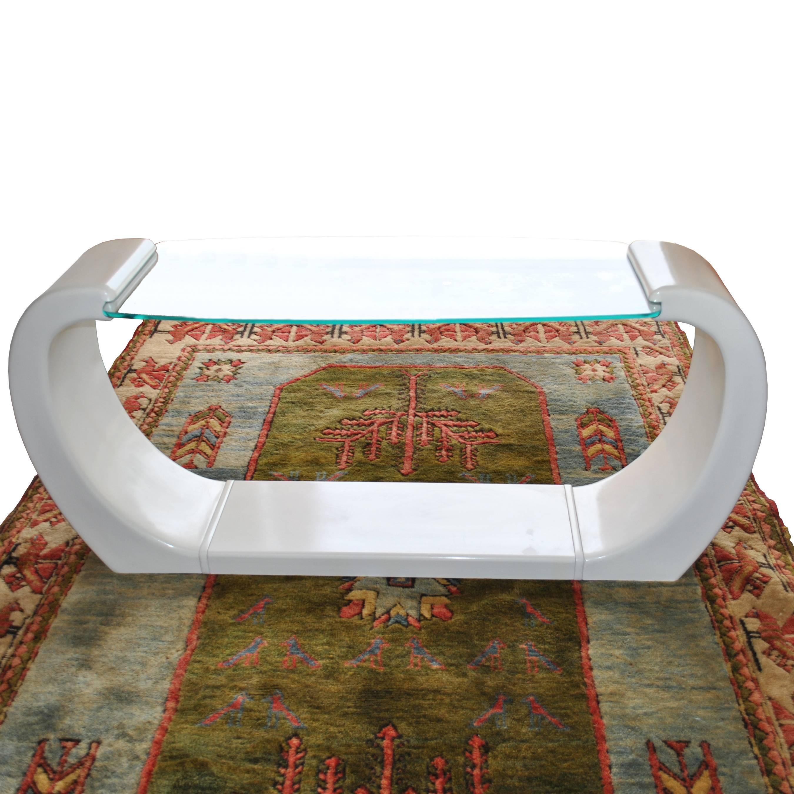 Une table console moderne de forme sculpturale en laque blanche avec un plateau en verre elliptique. Un design qui rappelle les œuvres de Karl Springer.