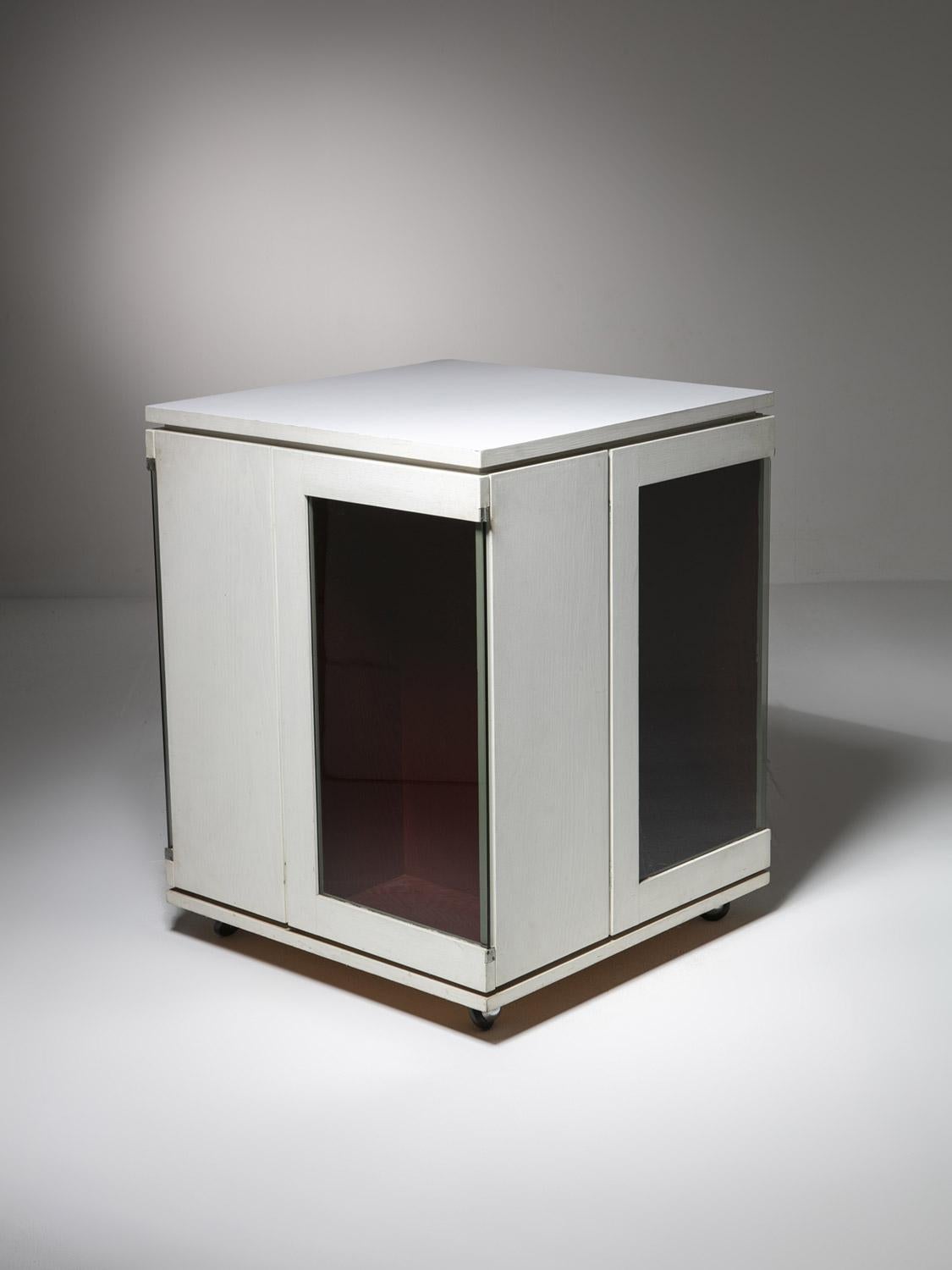 Bar sec fait sur mesure par Arrigo Rudi.
Pièce laquée blanche à quatre faces comportant une porte en verre de chaque côté.
Parties internes de couleur rouge.
L'architecte Arrigo Rudi a travaillé pendant de nombreuses années avec Carlo Scarpa et il a