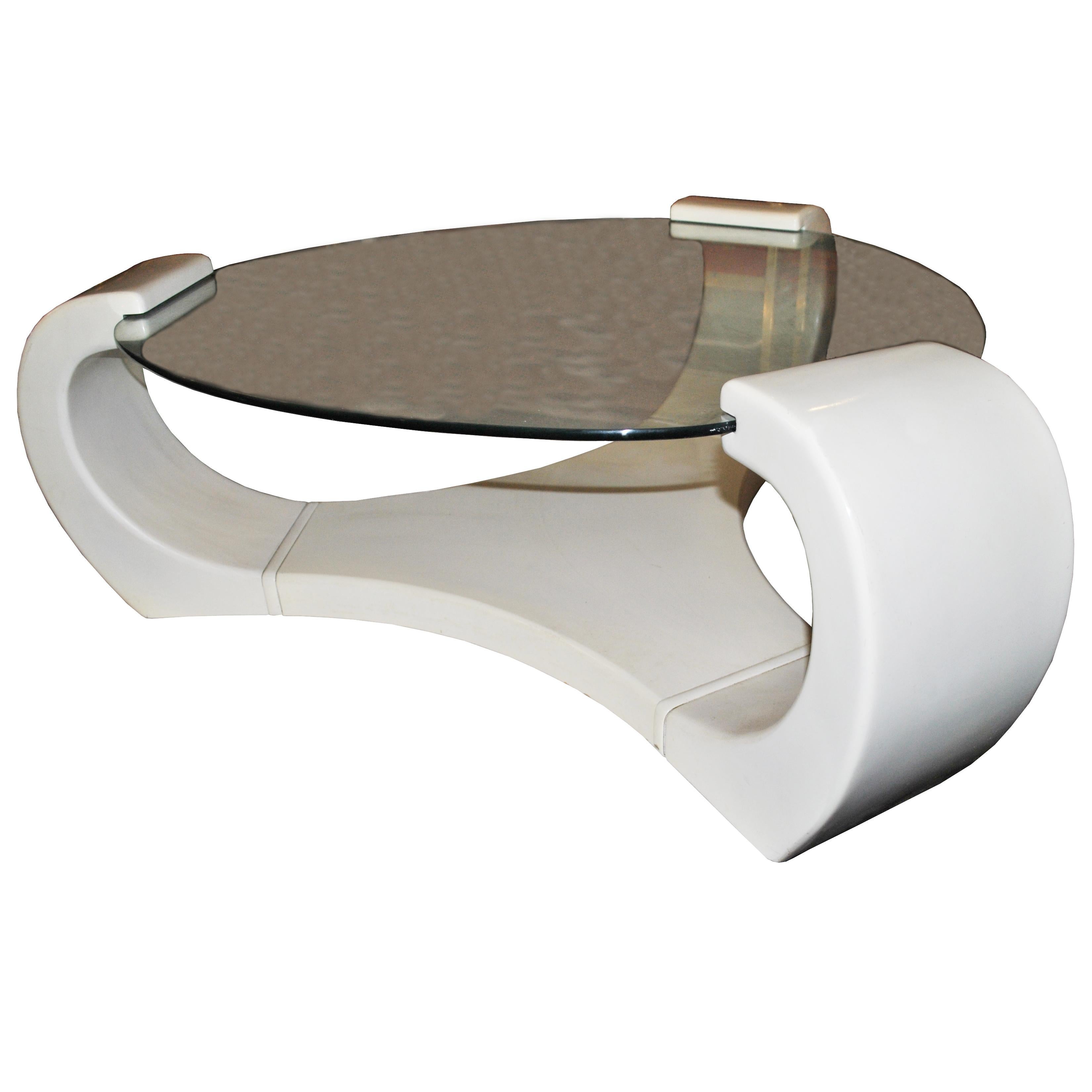 Ein moderner, skulpturaler Couchtisch aus weißem Lack mit einer runden Glasplatte. Ein Design, das an die Werke von Karl Springer erinnert.