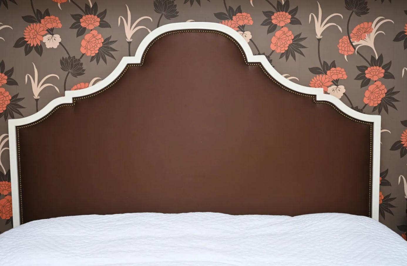 White lacquered shaped wood upholstered king size headboard from Hickory Chair. Upholstered in matte coffee satin with nailhead trim.
