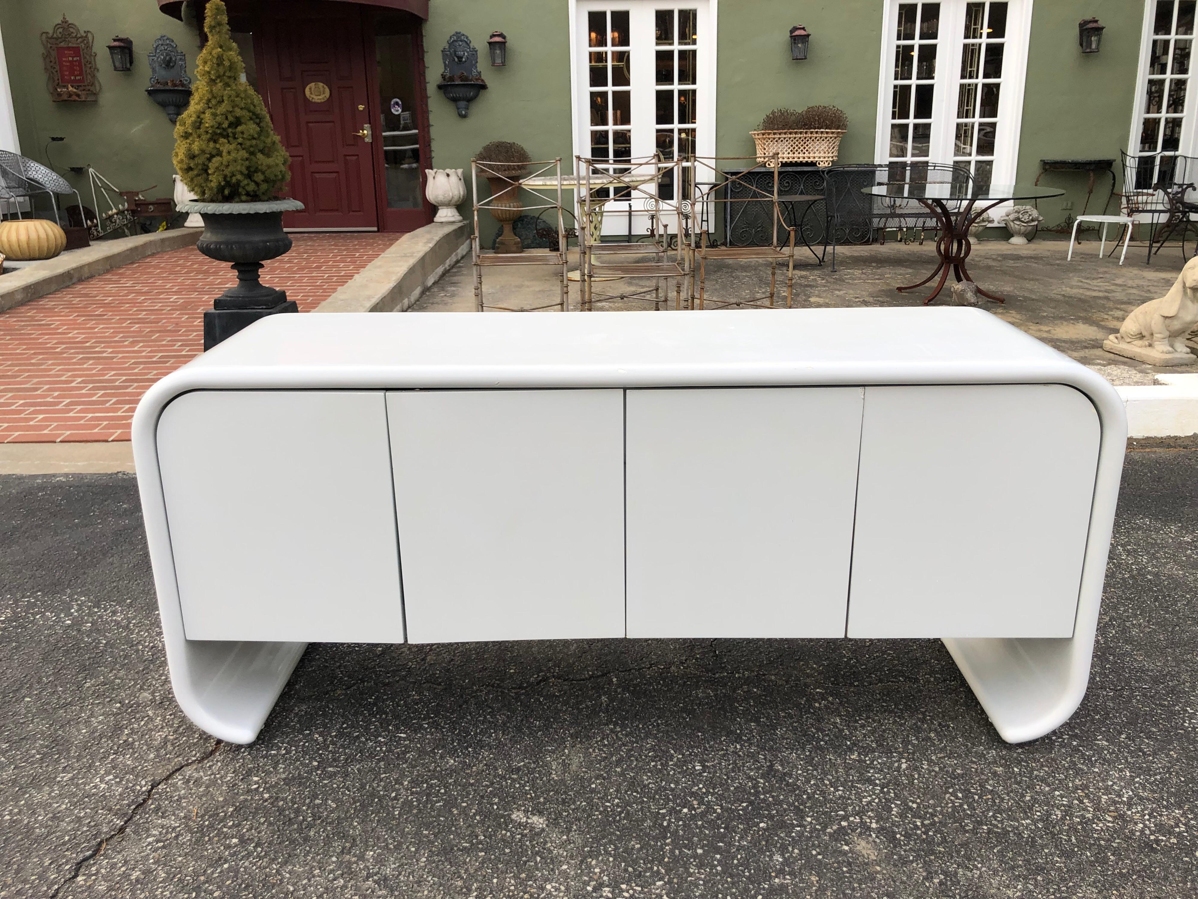 White lacquered Waterfall credenza in the style of Karl Springer. Possibly made by Ello Furniture. Amazing style and storage to this classic clean beauty. Four magnetic doors open up to cabinets each with single drawers. One is lined with felt for
