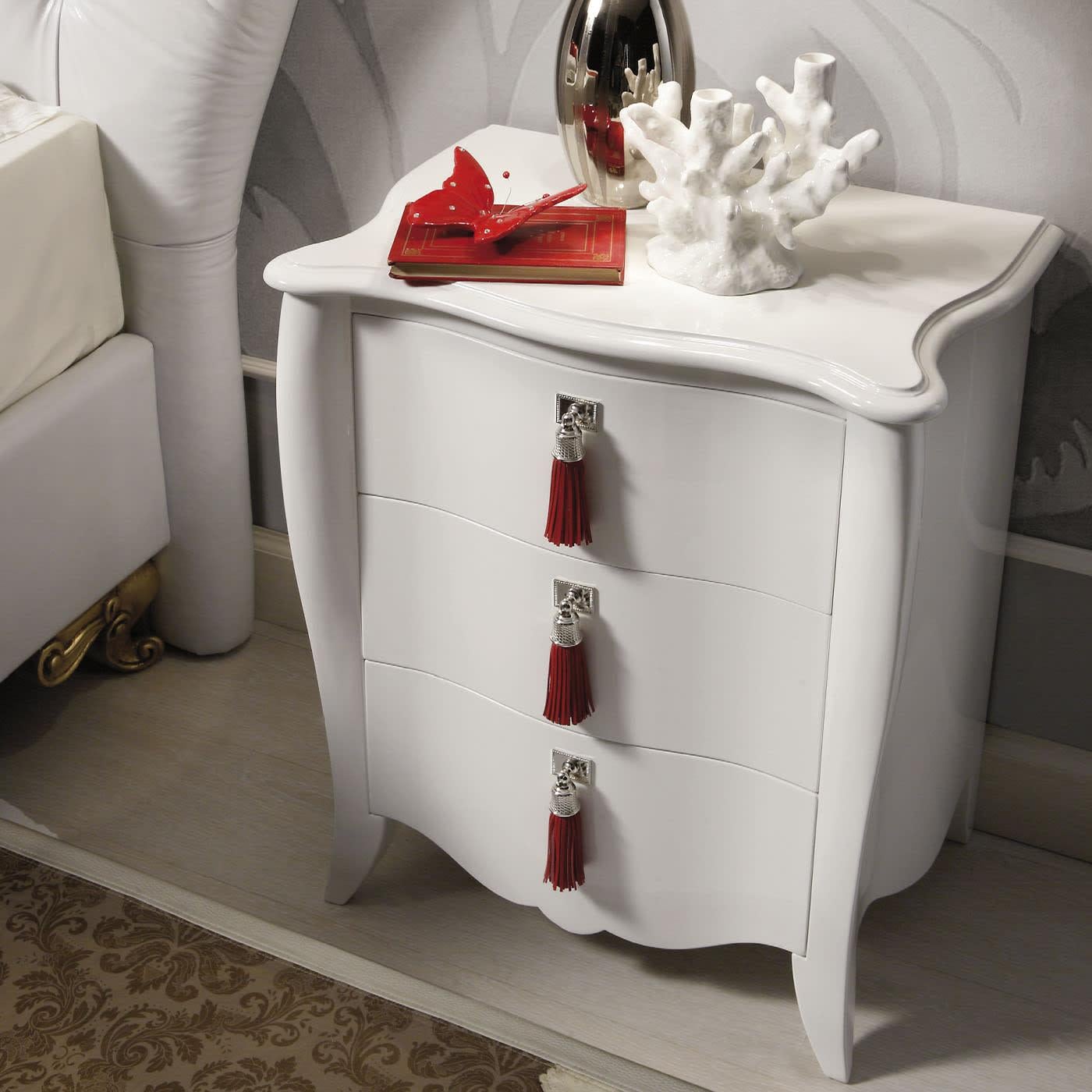 Discover this white nightstand in lacquered wood with three drawers by Ros Italia Interiors. The handles are in leather and metal with a silver finishing. Please, contact the Concierge service for further information.