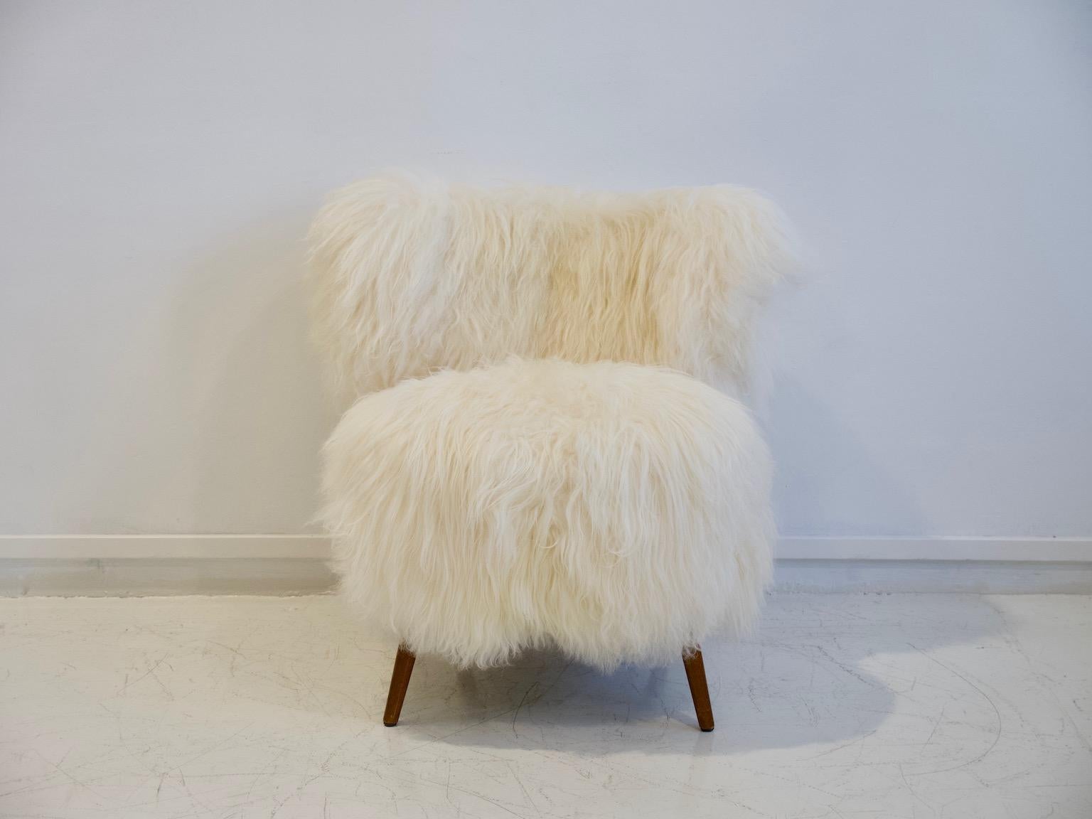 Lounge chair made in Denmark, circa 1950. Later upholstered with long-haired Icelandic lambskin. Legs made of lacquered wood.