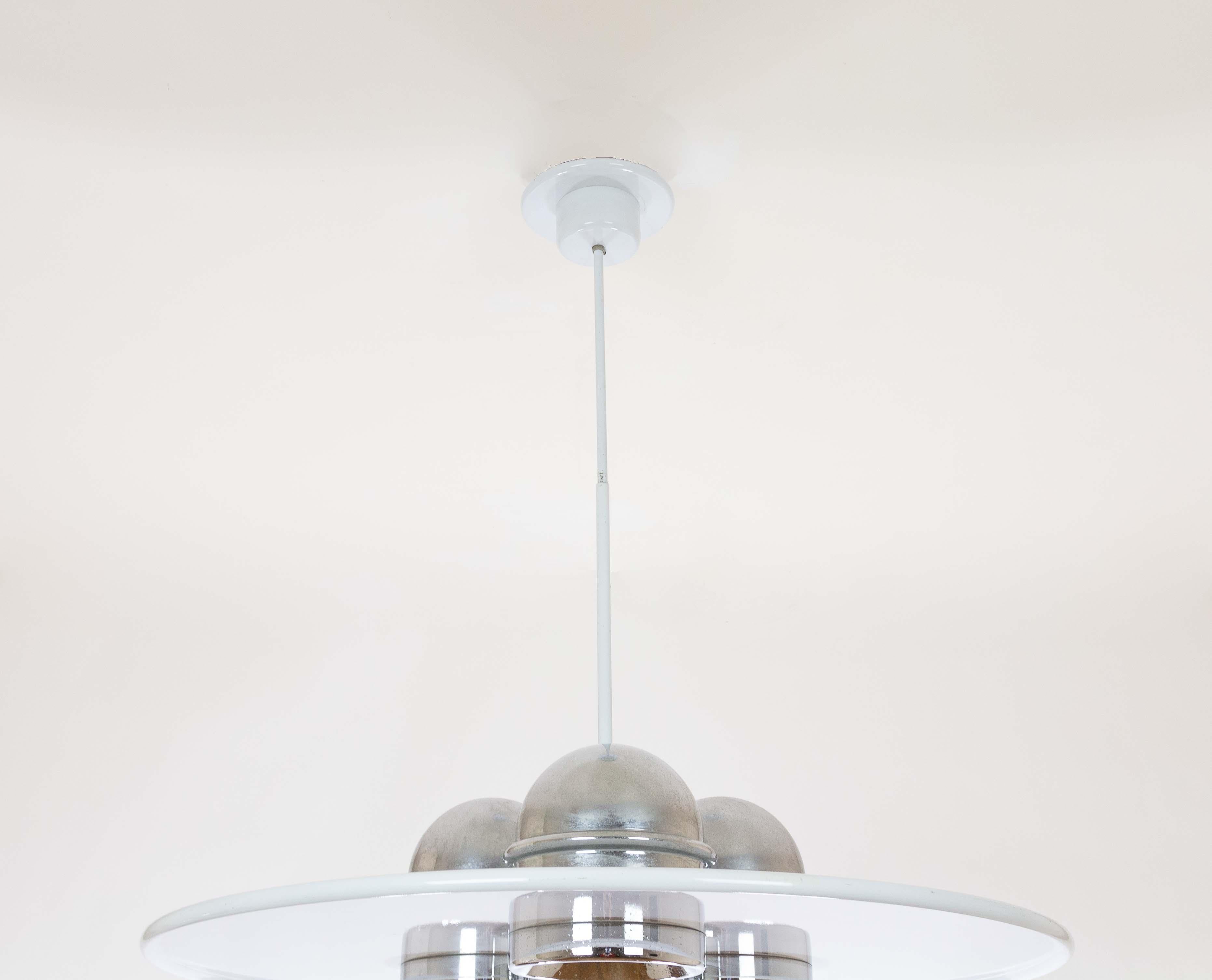 Large Lampros pendant designed by Ettore Sottsass Jr. and produced by Stilnovo in the 1970s.

This disc-shaped model consists of a white aluminium shade and three chromed metal reflectors. It has the manufacturer's mark engraved at the top of the