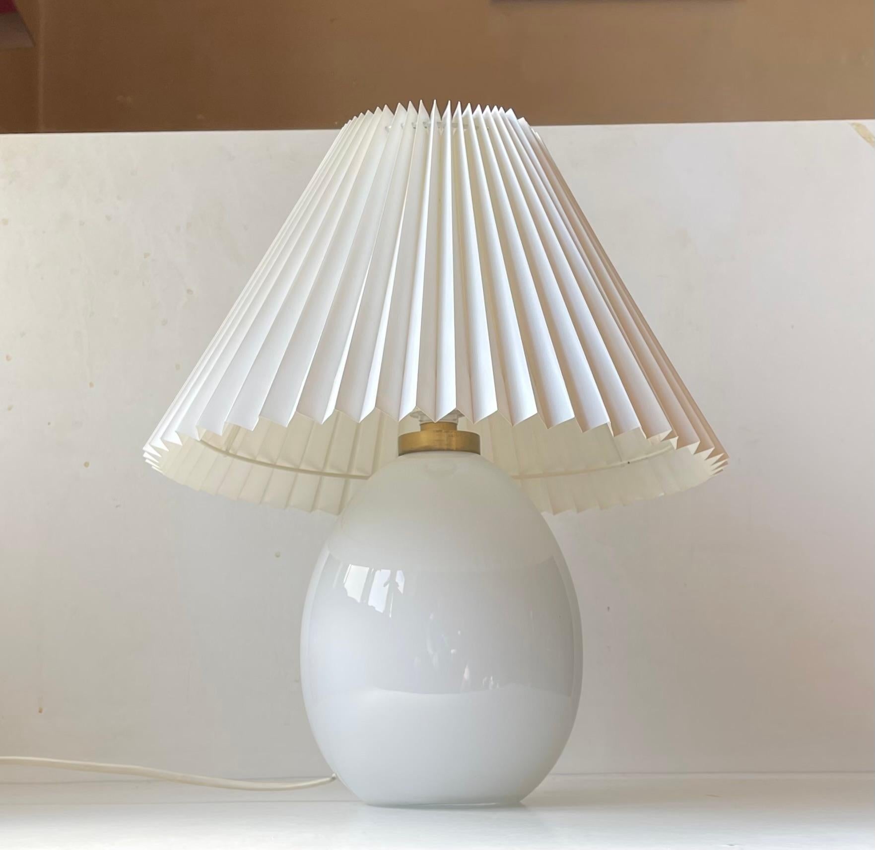 Egg shaped white opaline glass table lamp designed by Poul Seest Andersen and manufactured by Le Klint and Holmegaard in Denmark during the late 1970s or early 80s. It features a pin-on/of switch, a brass top and makers marks to the base. It comes