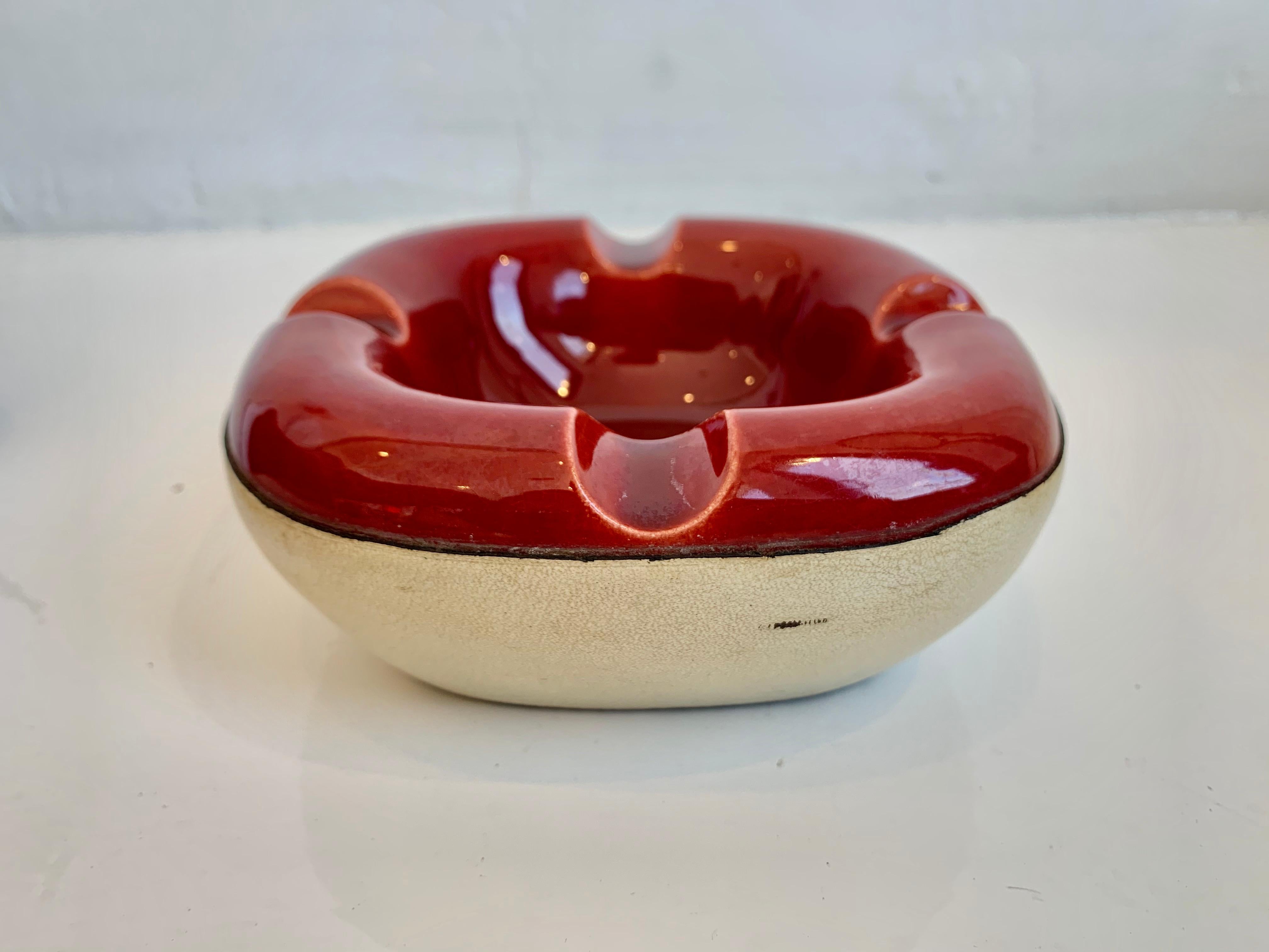 Handsome leather and ceramic ashtray/catchall by Longchamp. Stamped with Lonchamp - France and logo. White leather base with contrast stitching. Deep red ceramic dish sewn into leather. Great sculptural piece. Great ashtray or bowl for keys by the