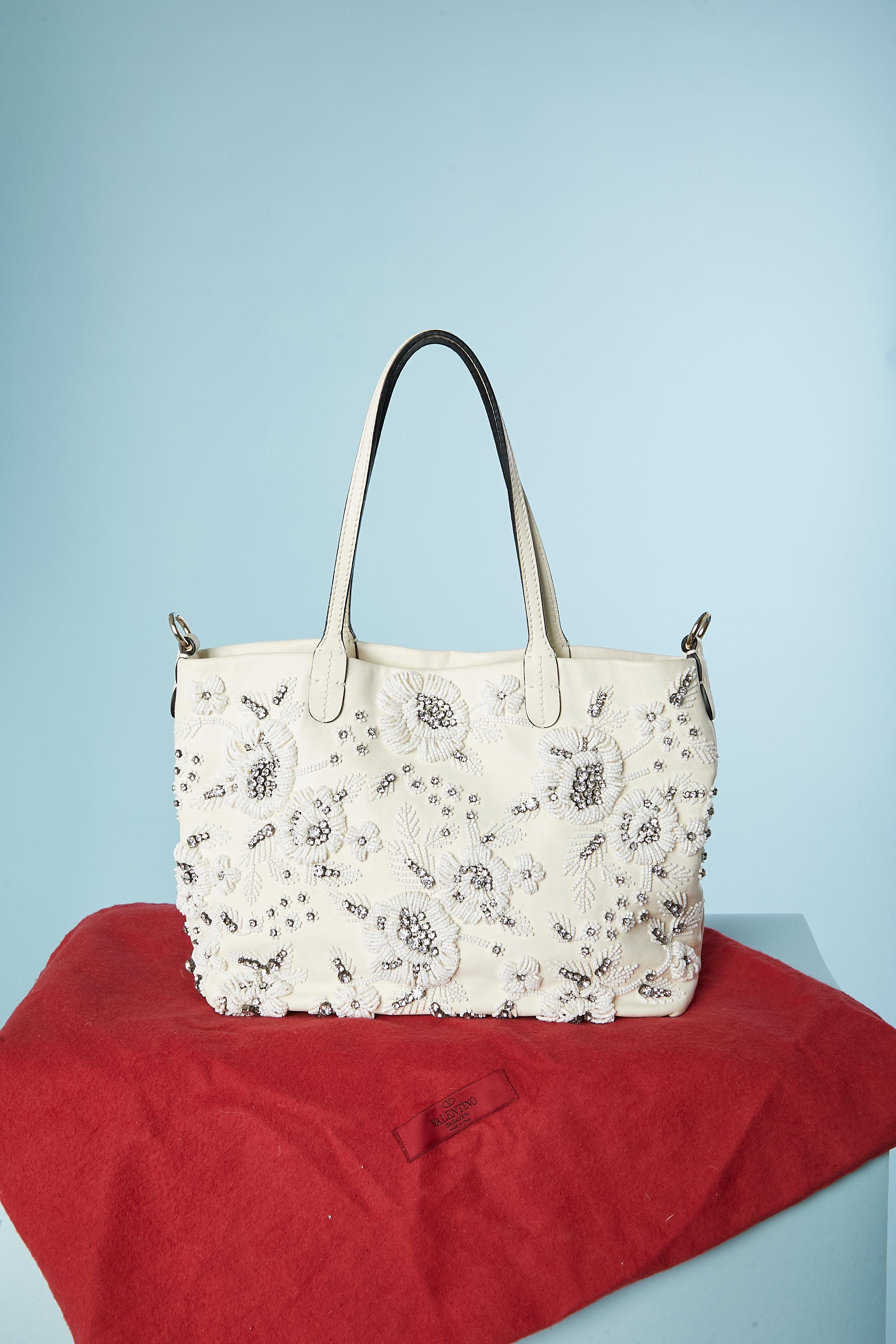 White leather handbag with rhinestone and beads embroideries . Cotton lining. 3 inside pockets including one with zip closure. Snap closure on the top middle front . Gold metallic studs underneath. 
SIZE: 38 cm X 23cm X 9 cm . Handle strap lenght=