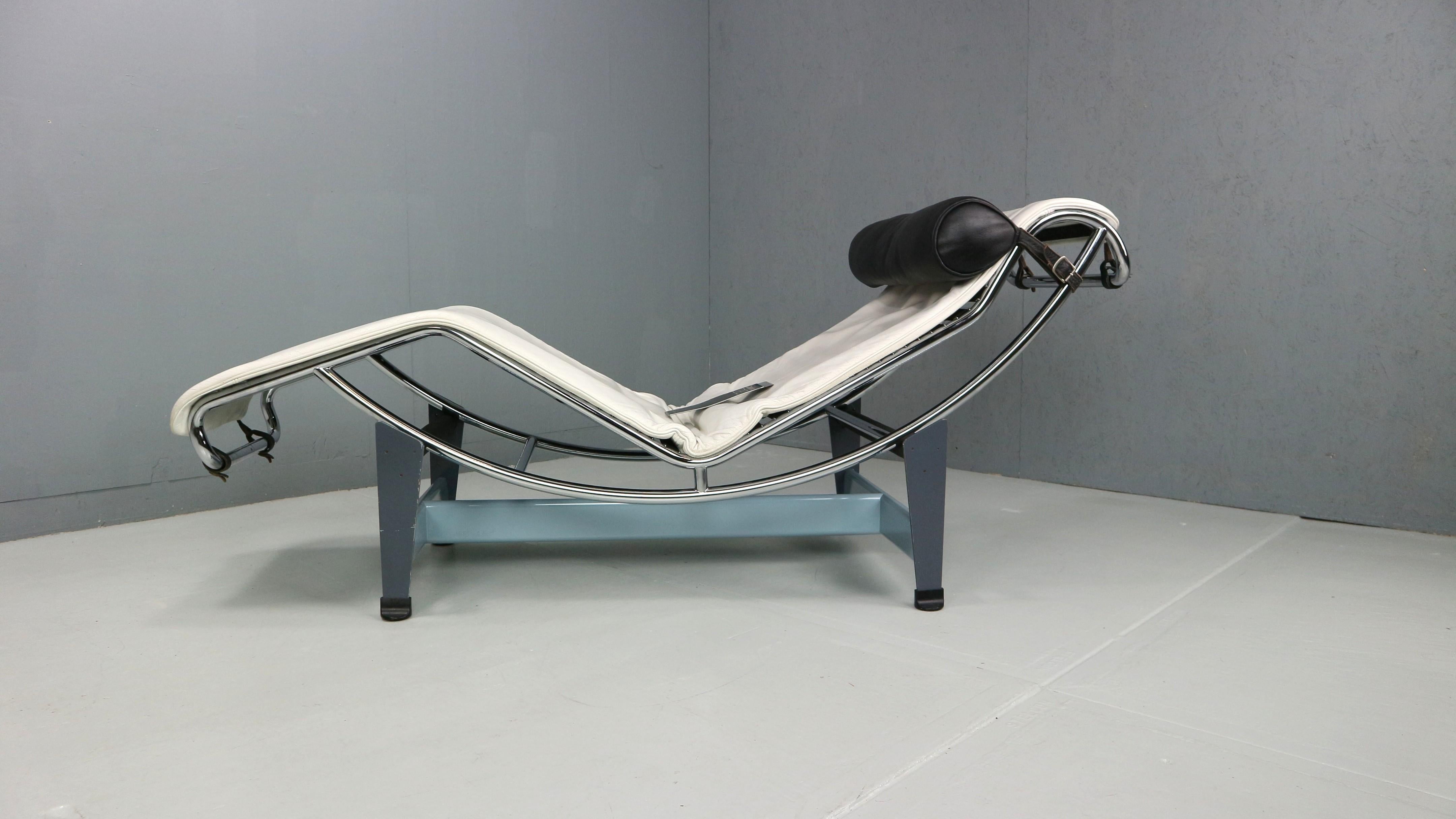 Chaise-longue con struttura bicolore, barra trasversale in acciaio con sezione a goccia in azzurro e quattro barre di supporto in grigio basalto. Il pad del materasso è in pelle bianca. Il poggiatesta imbottito in poliestere è in pelle nera. Questo