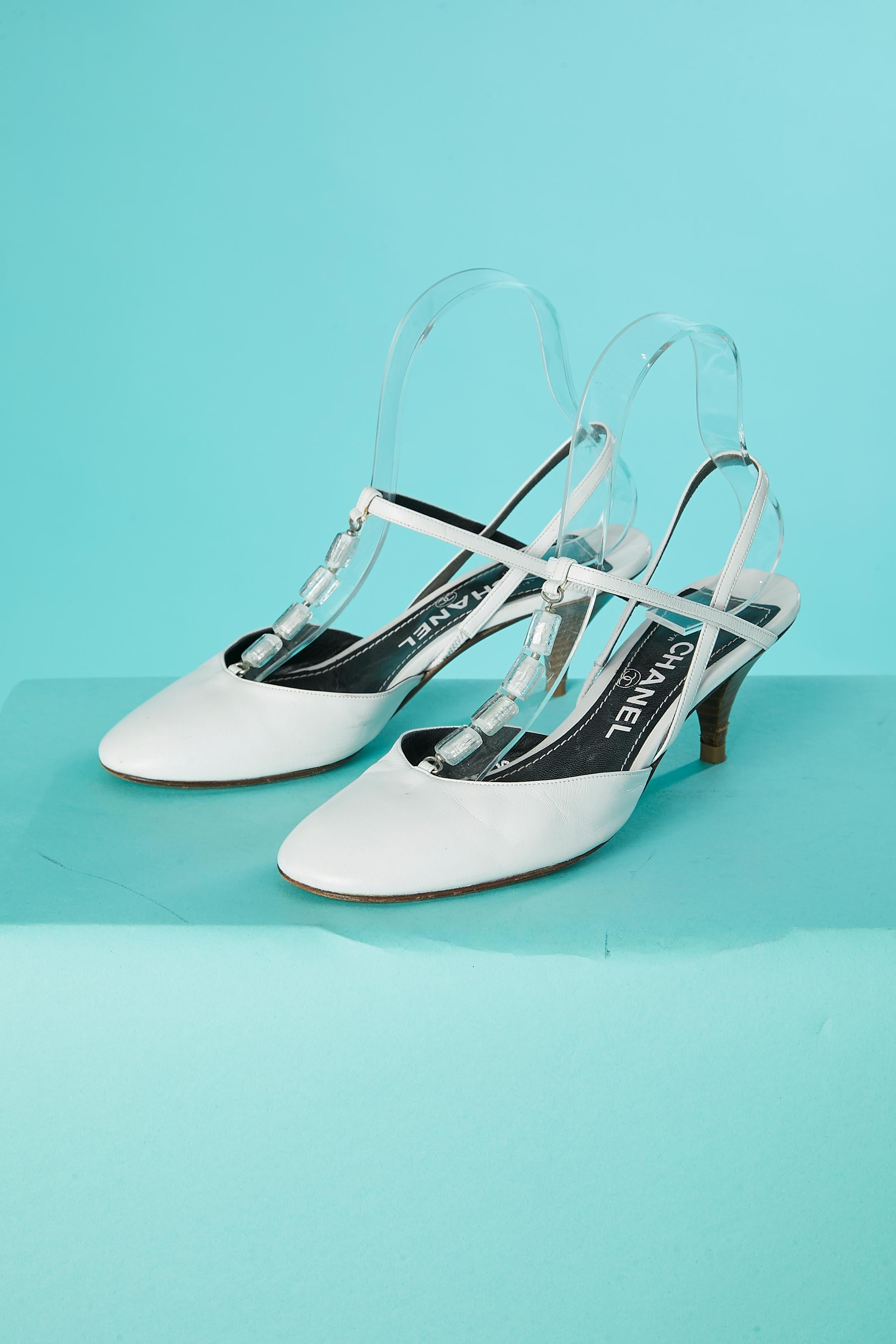 Sandali in pelle bianca con perline di vetro. Elastico corto sui cinturini all'interno del sandalo. 
Altezza del tacco: 6 cm
TAGLIA DELLE SCARPE: 38