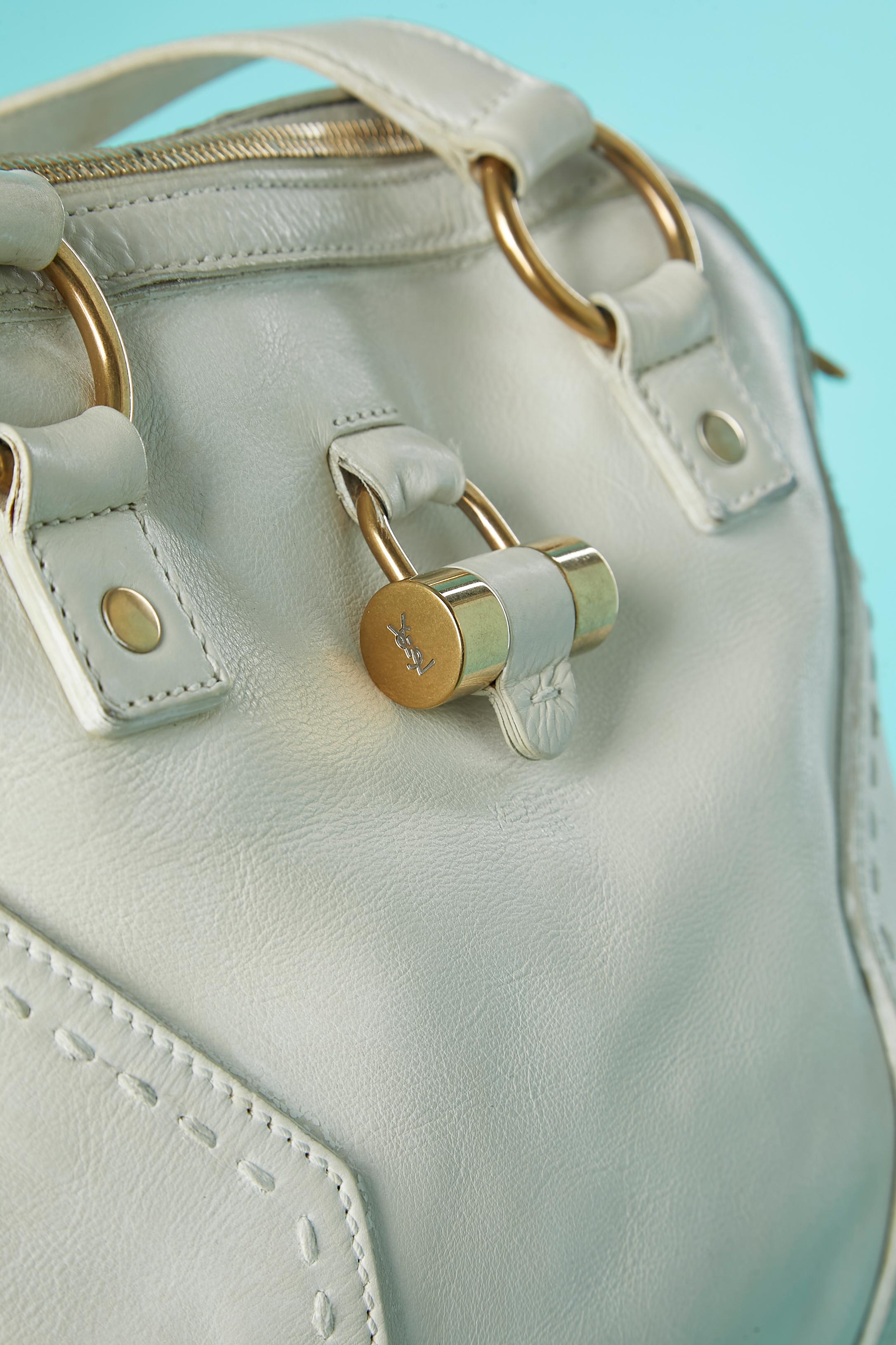 Borsa a manico alto in pelle bianca con lavorazione a taglio e impunture. Hardware in metallo dorato e armadietto con chiave e portachiavi. Chiusura con zip centrale in alto. 2 tasche interne (una con chiusura a zip, una senza) Fodera in raso
