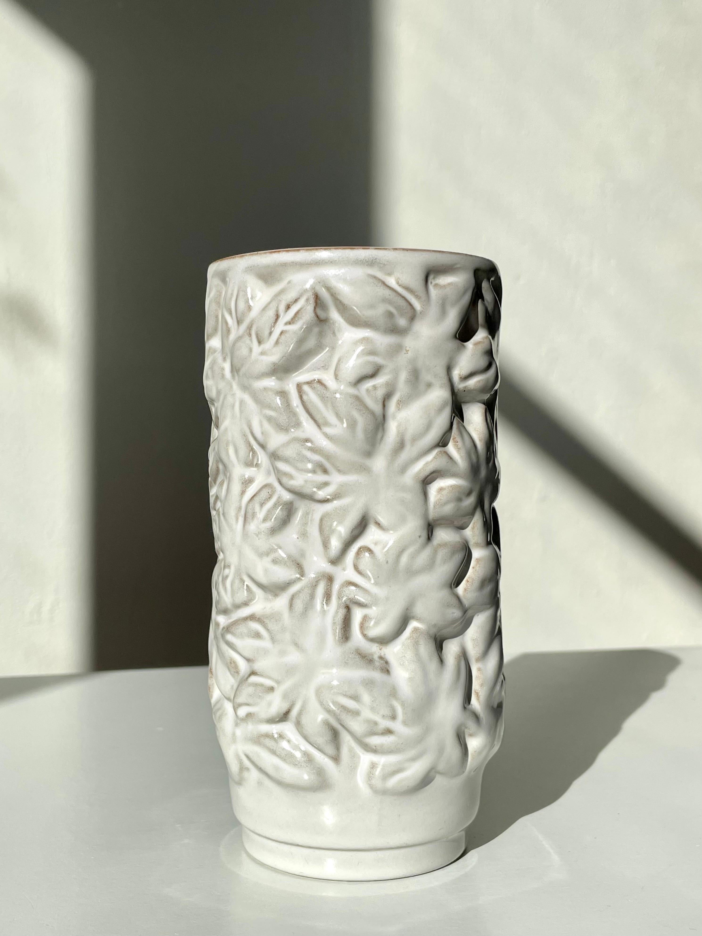Handmade ceramic cylinder shaped vase with relief leaves under white shiny glaze. Manufactured in Denmark in the 1950s. Stamped under base. Beautiful vintage condition. 