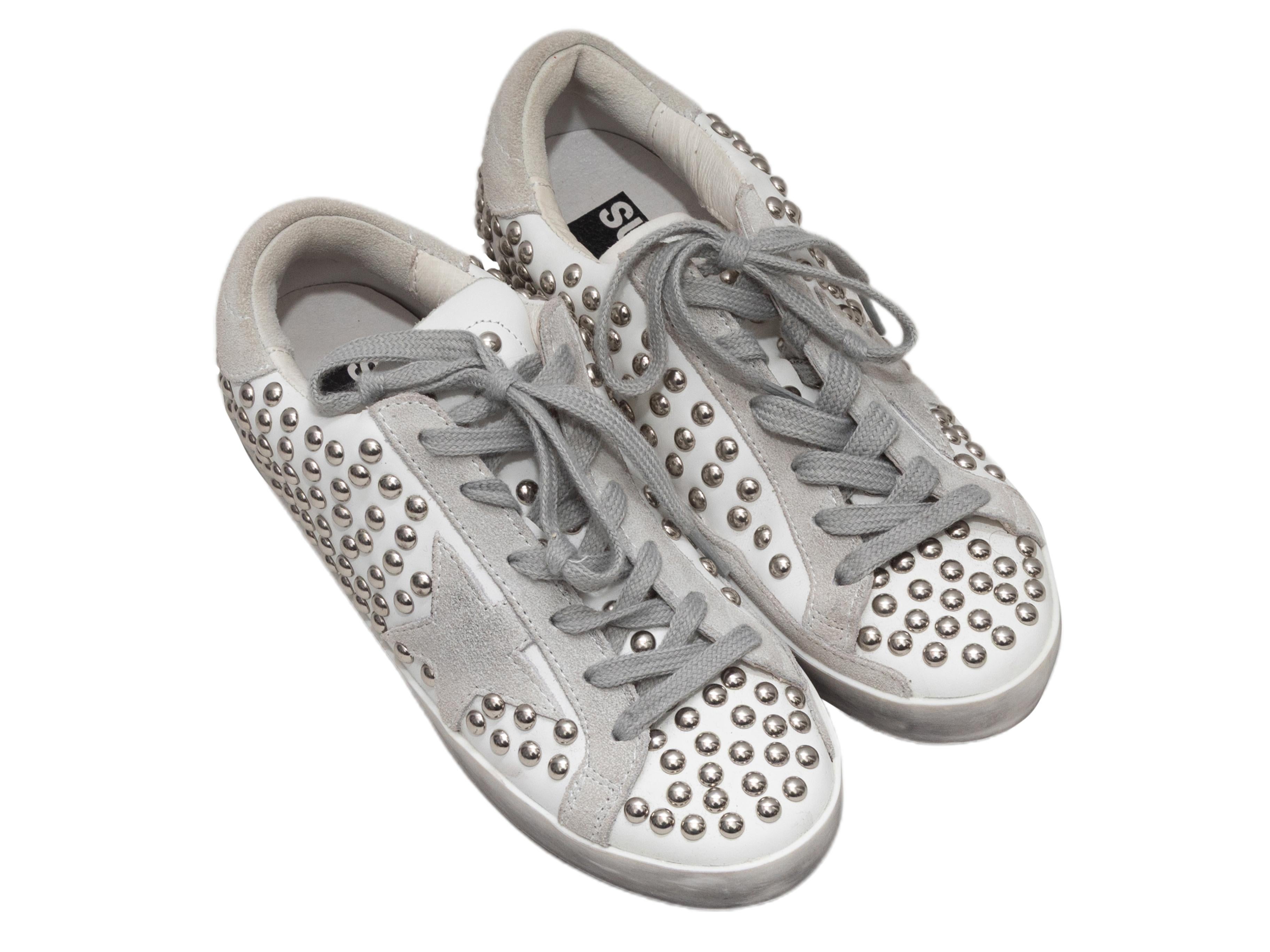 White leather and light grey suede studded low-top sneakers by Golden Goose. Silver-tone hardware. Rubber soles. Lace-up tie closures at tops. 2.75