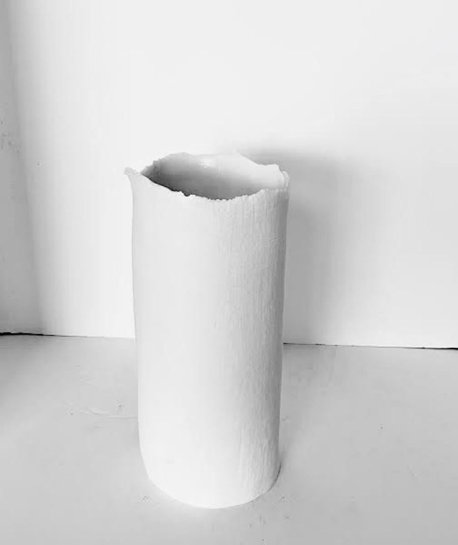 Contemporary French handmade white fine ceramic cylinder shaped vase is a one of a kind piece.
The vase is fine ceramic with a textured surface that looks like linen.
The mouth of the vase has an unfinished rough edge detail.
A collection of five