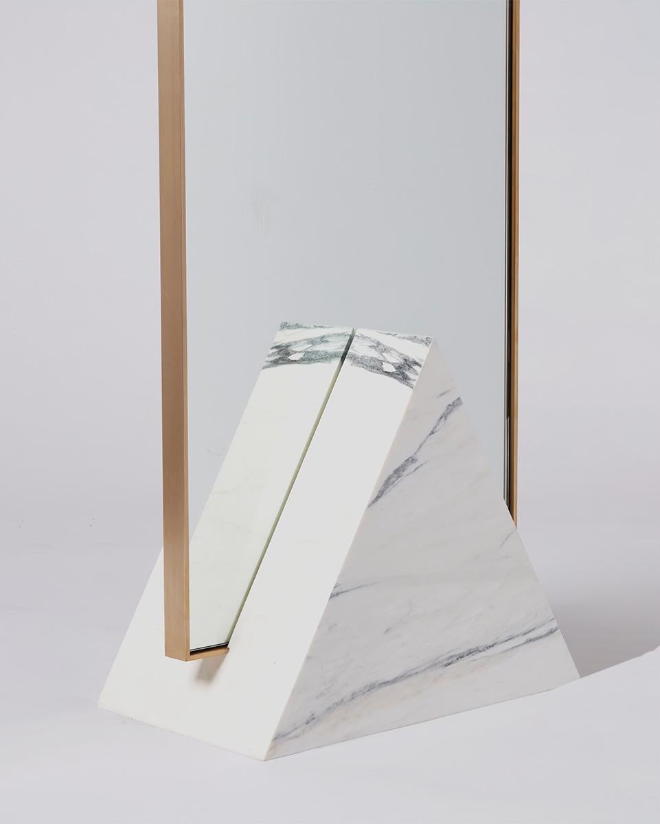 Tri coexist standing consists of a triangular white marble base, polished brass mirror frame, and recycled rubber. The mirror is a functional piece of furniture that doubles as a sculpture.

The brass framed mirror fits into a rich veined