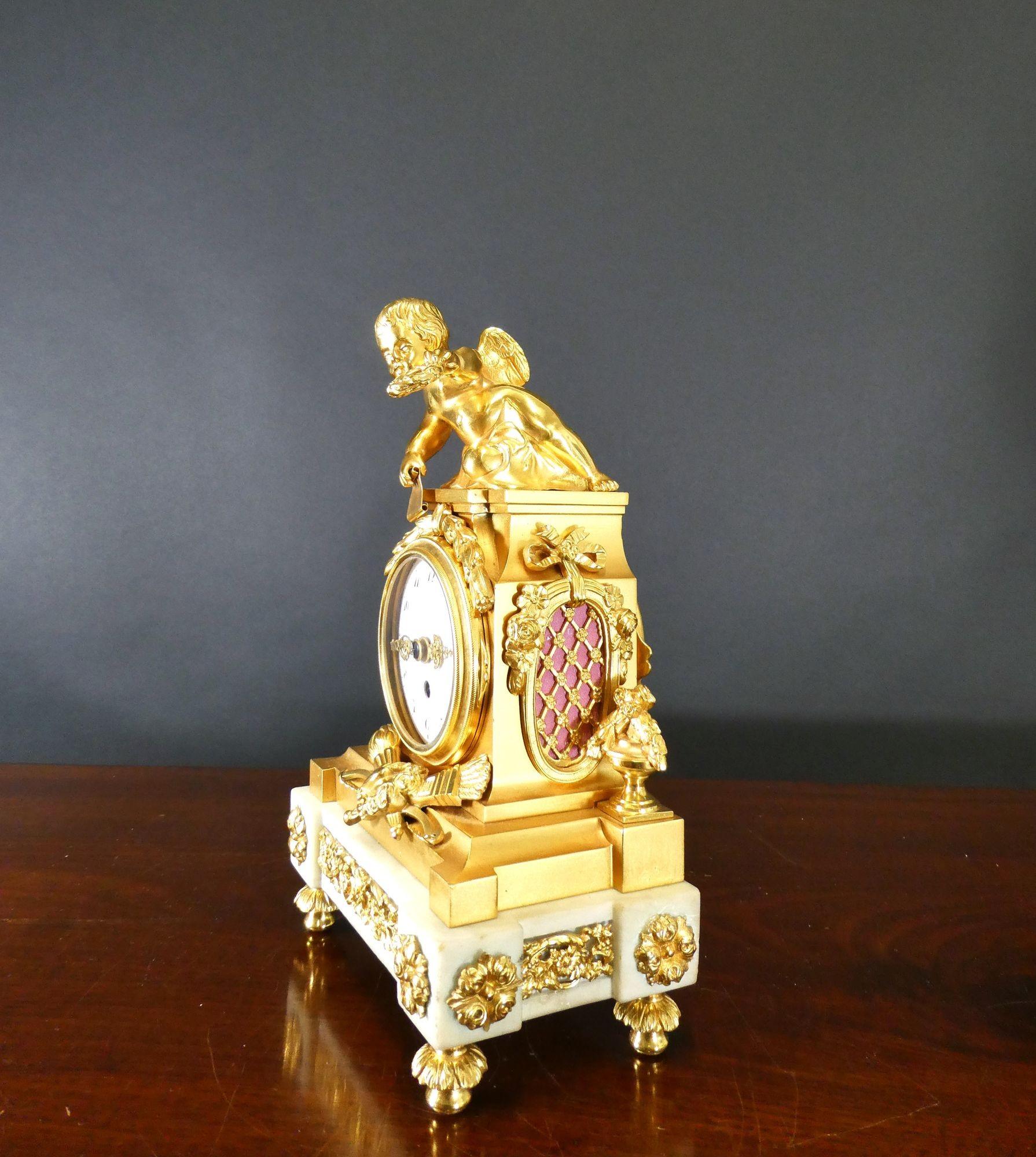 White marble and ormolu mantel clock
Housed in a white marble case with stepped plinth and applied decorative mounts and surmounted by a cherub, resting on decorative feet.

Enamel dial with Arabic numerals and original hands.
Eight day movement
