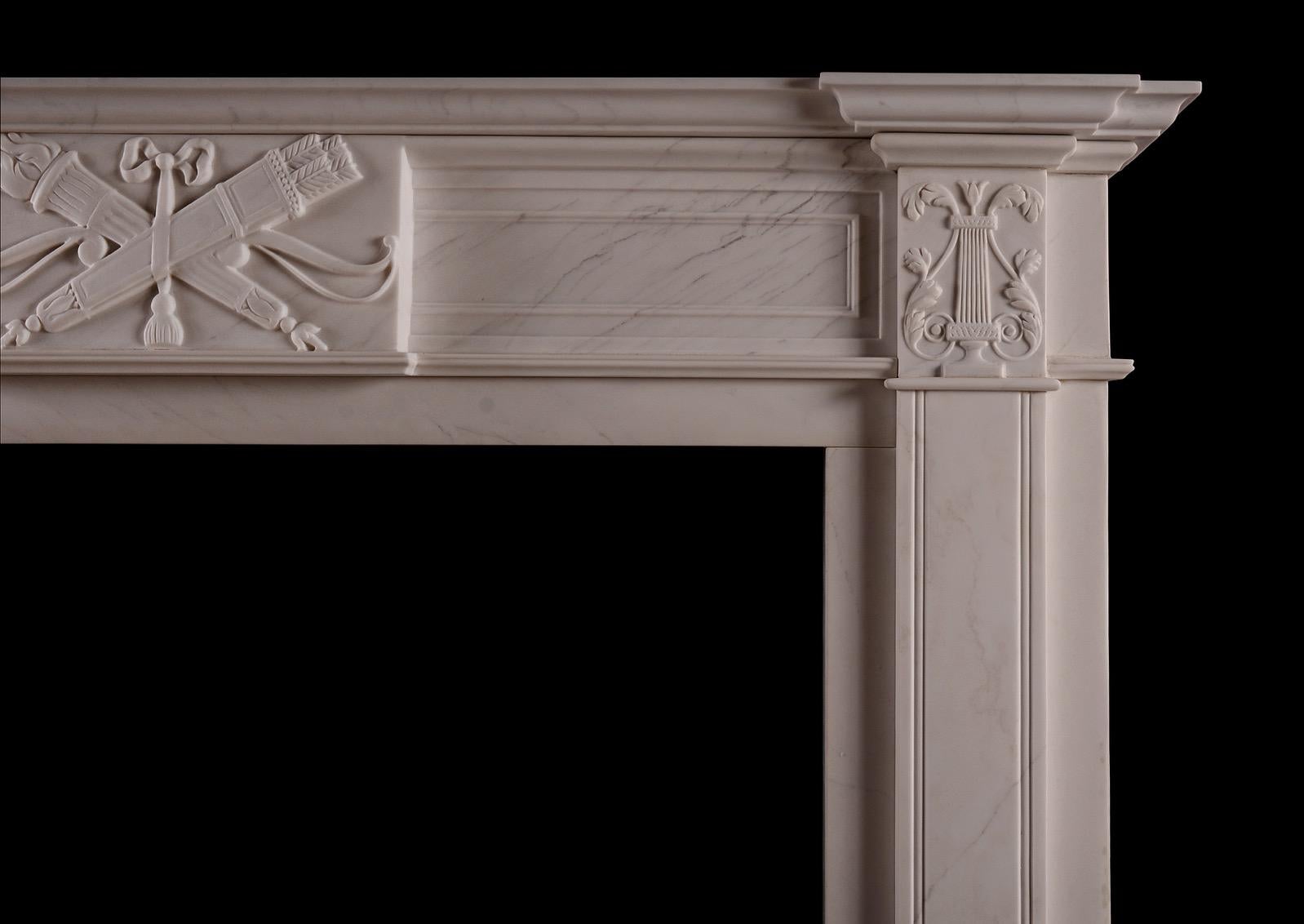 A white marble fireplace in the late Georgian style. The frieze with carved centre blocking featuring quiver, torch and tied ribbon, with carved lyres to end blocks. Panelled frieze and jambs, and breakfront moulded shelf above. Based on an original