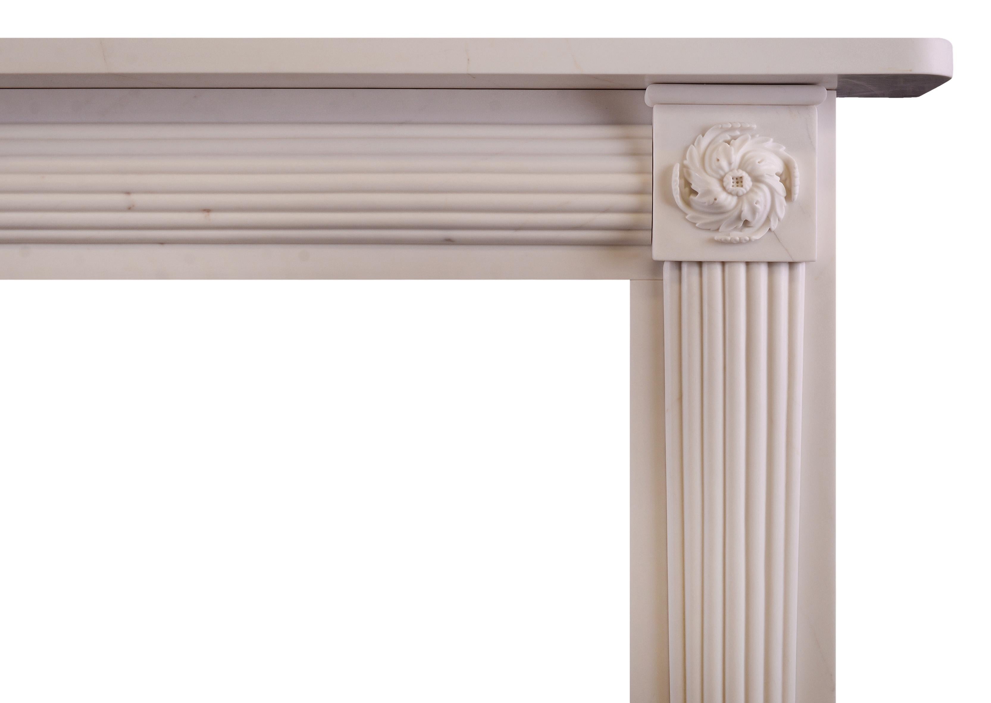 A Regency style white marble fireplace. The tapered, reeded jambs surmounted by finely carved swirling finials. The frieze with convex reeding throughout. Plain shelf above. An elegant piece, well suited for smaller Drawing Room or Bedroom. Modern.