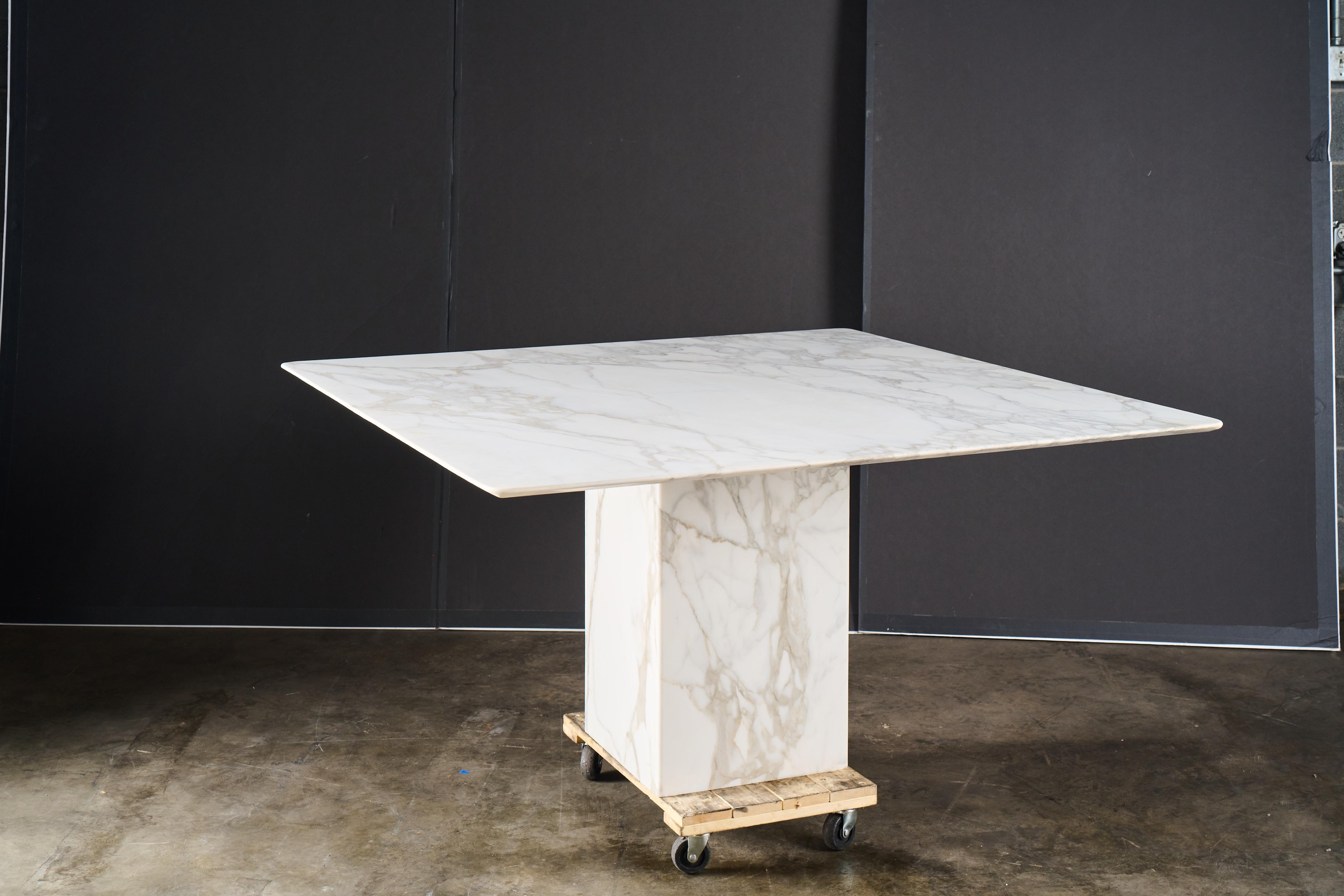 Si tratta di un tavolo da pranzo in stile contemporaneo, probabilmente della fine del XX secolo, caratterizzato da un design elegante e minimalista. Il tavolo presenta un piano quadrato in marmo lucido con bellissime venature e una base con