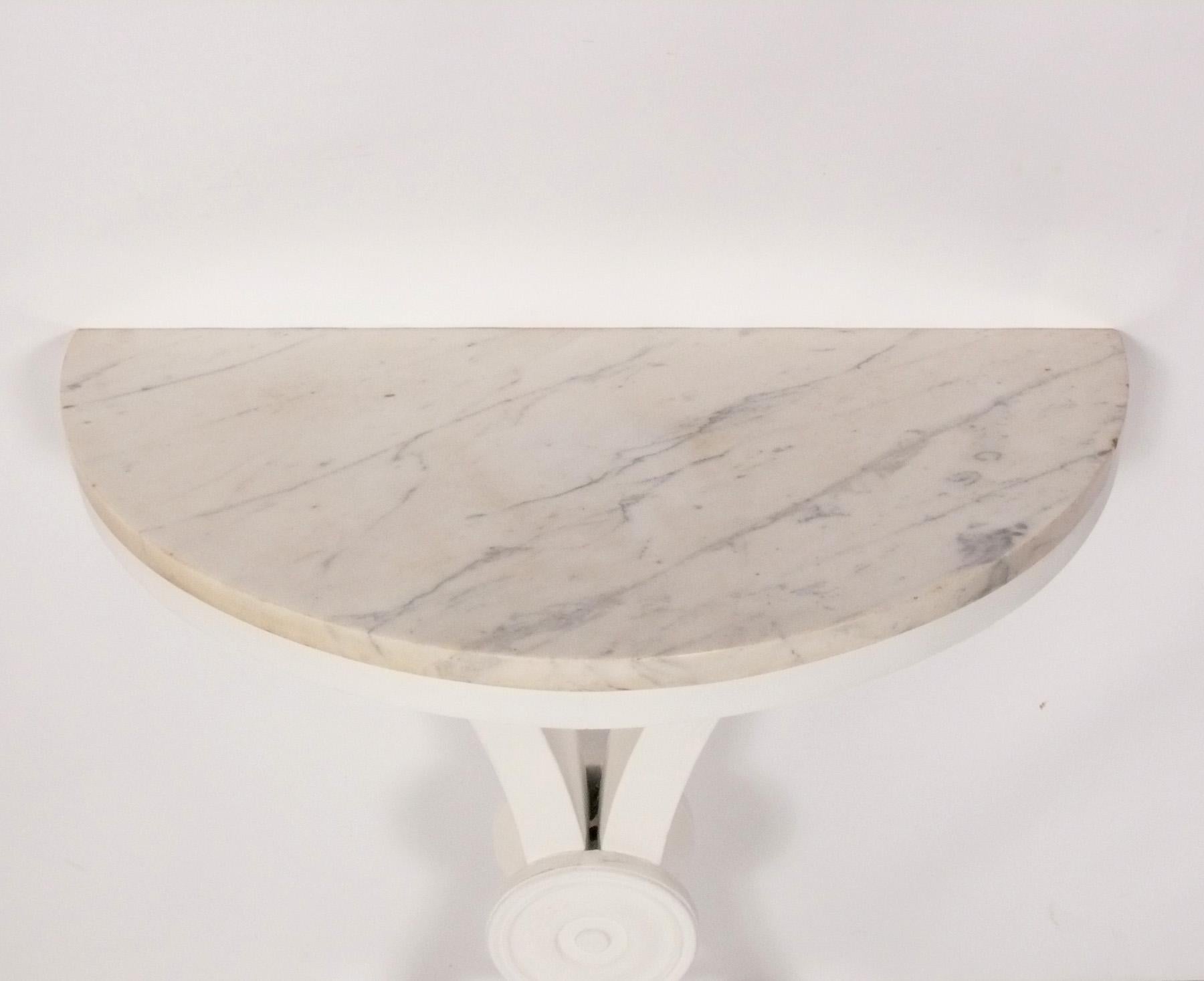 Elegant White Marble Top Demilune Wall Mounted Console Table, American, circa 1940s. It is constructed of a white marble top with a wooden wall mounted base in a chalky white painted finish. 