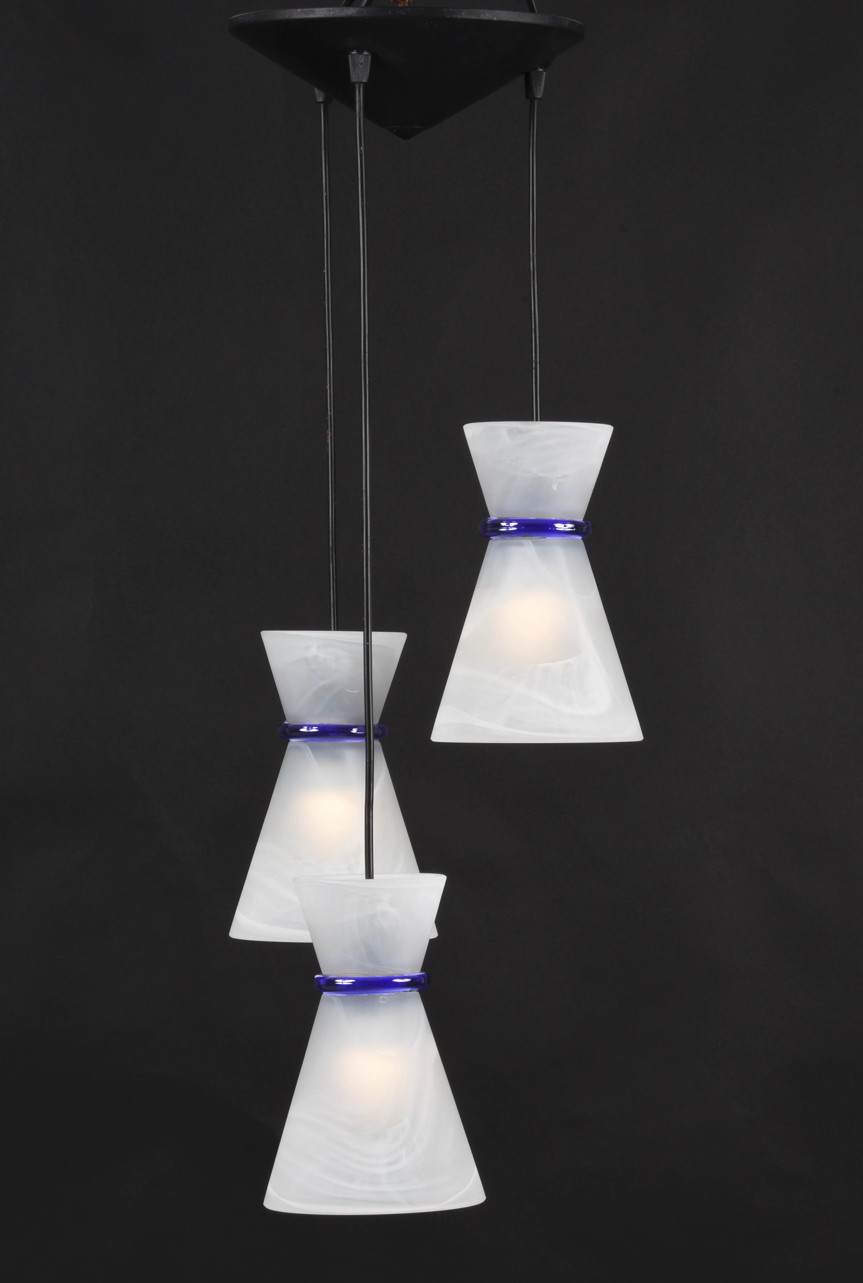 Fantastic white marbled Murano glass Italian chandelier with three pendant lights. This amazing piece was designed in Italy during the 1980s.

These three pendants have marbled white cones and a blue Murano glass ring. Every single pendant has a