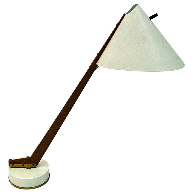 The classic and lovely table/desk lamp model B54 designed by Hans-Agne Jakobsson for Markaryd, Sweden - around 1955. The lamp has a white painted metal shade, arm of  solid teak and a heavy brassfoot. Swivel function and original light switch on the