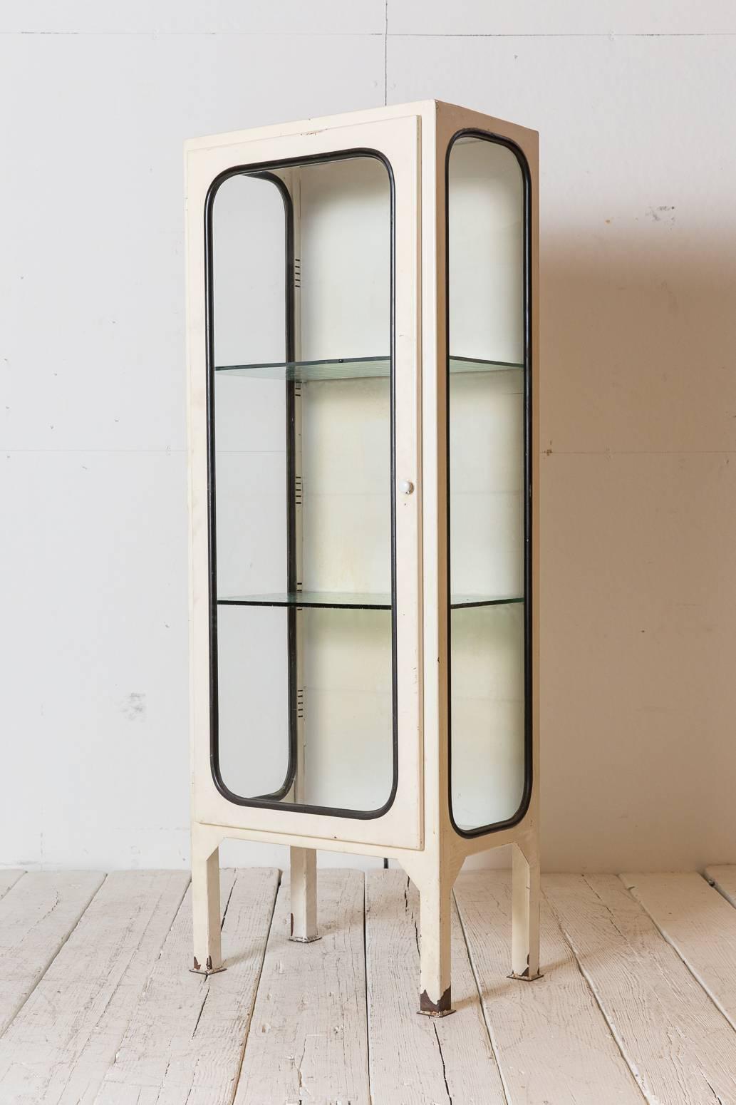 White metal apothecary cabinet with glass shelves.