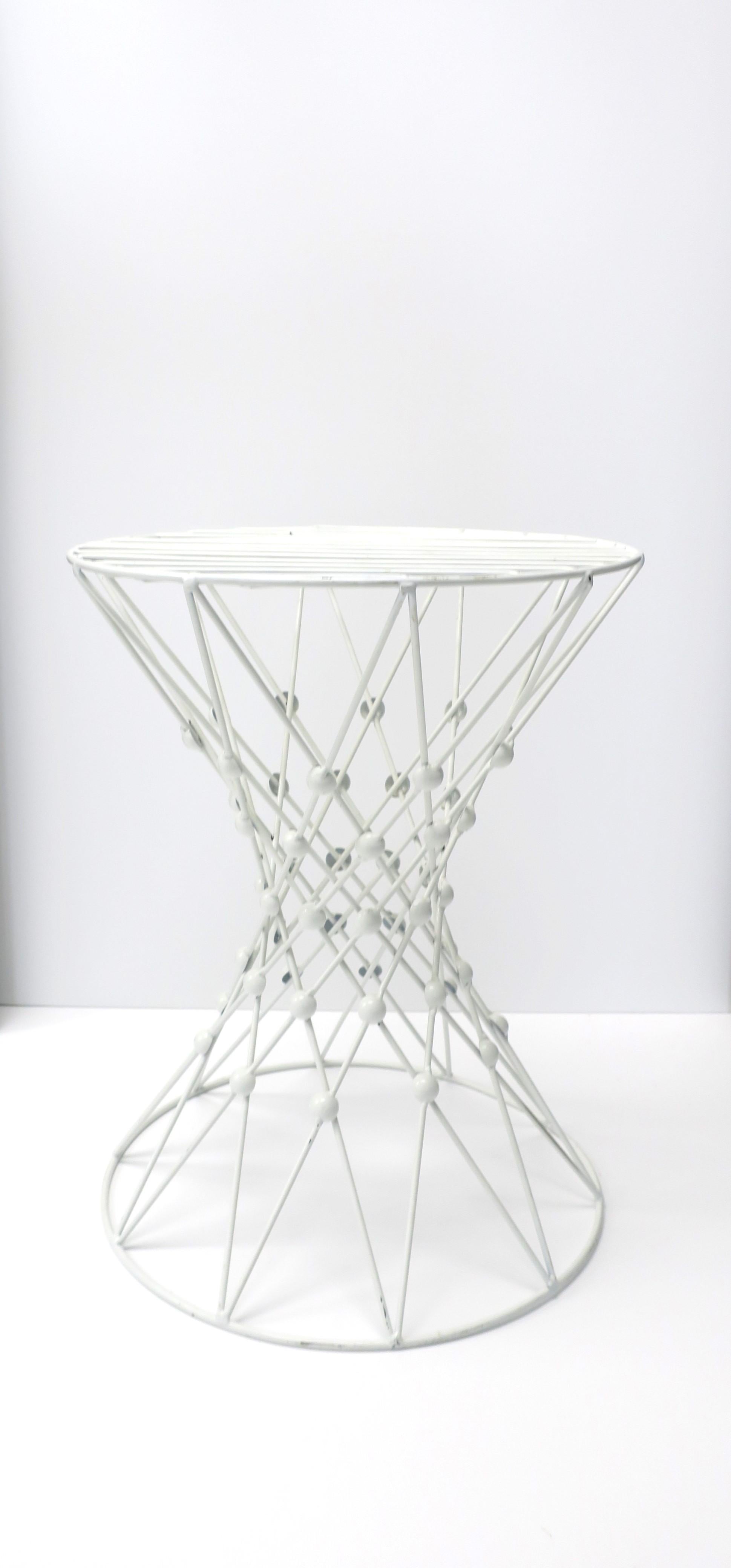 A white enamel and metal side table with a crisscross design and hourglass shape. A versatile side, accent, or drinks table, etc. Dimensions: 15.38