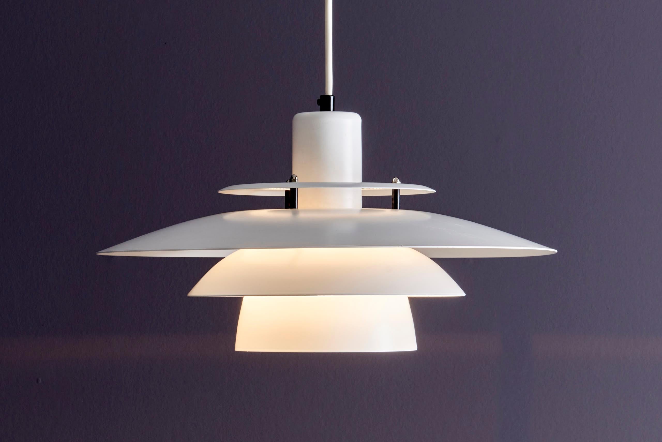 Lámpara colgante de metal blanco inspirada en la emblemática serie PH de Poul Henningsen. El diseño de la pantalla en capas proporciona una luz suave y sin reflejos, por lo que es perfecta para comedores, cocinas o salas de estar. Fabricada en metal