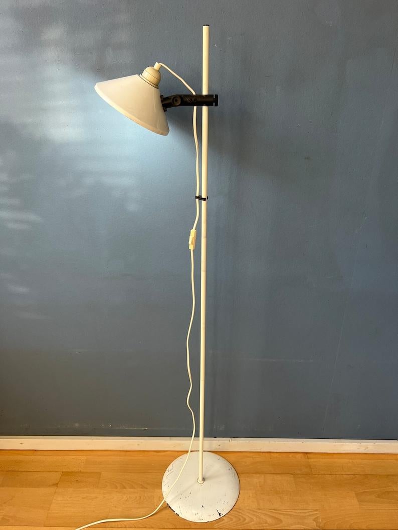 Mid century white woja floor lamp. The lamp is made out of metal and has a white lacquer. The shade can be moved up and down the base and positioned in any direction desirable. The lamp requires one E26/27 lightbulb and currently has an EU-plug