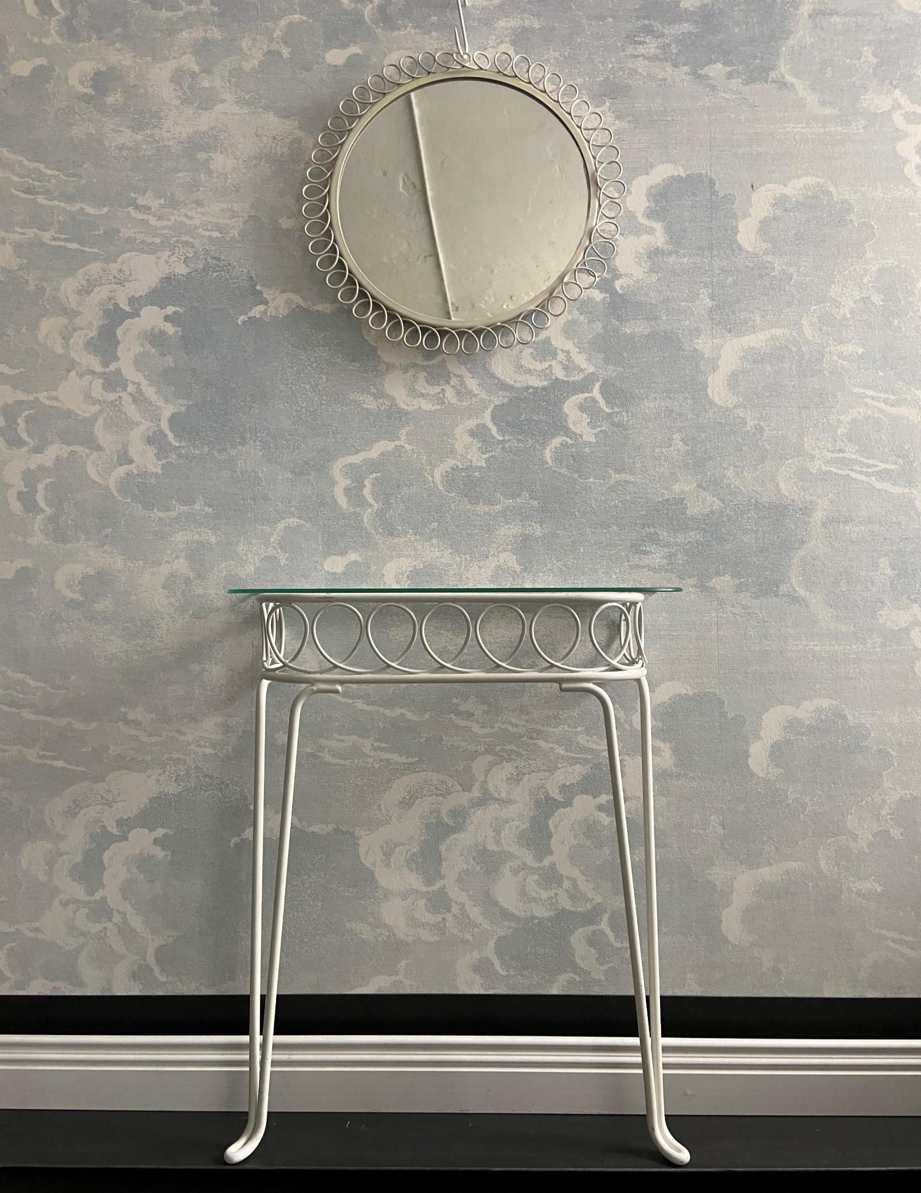 This gorgeous ensemble consisting of a metal wall console table and a mirror is made from solid white lacquered metal.

The design is very much of the 1950's and 1960's with elegantly shaped hairpin legs and a looping metal band connecting the