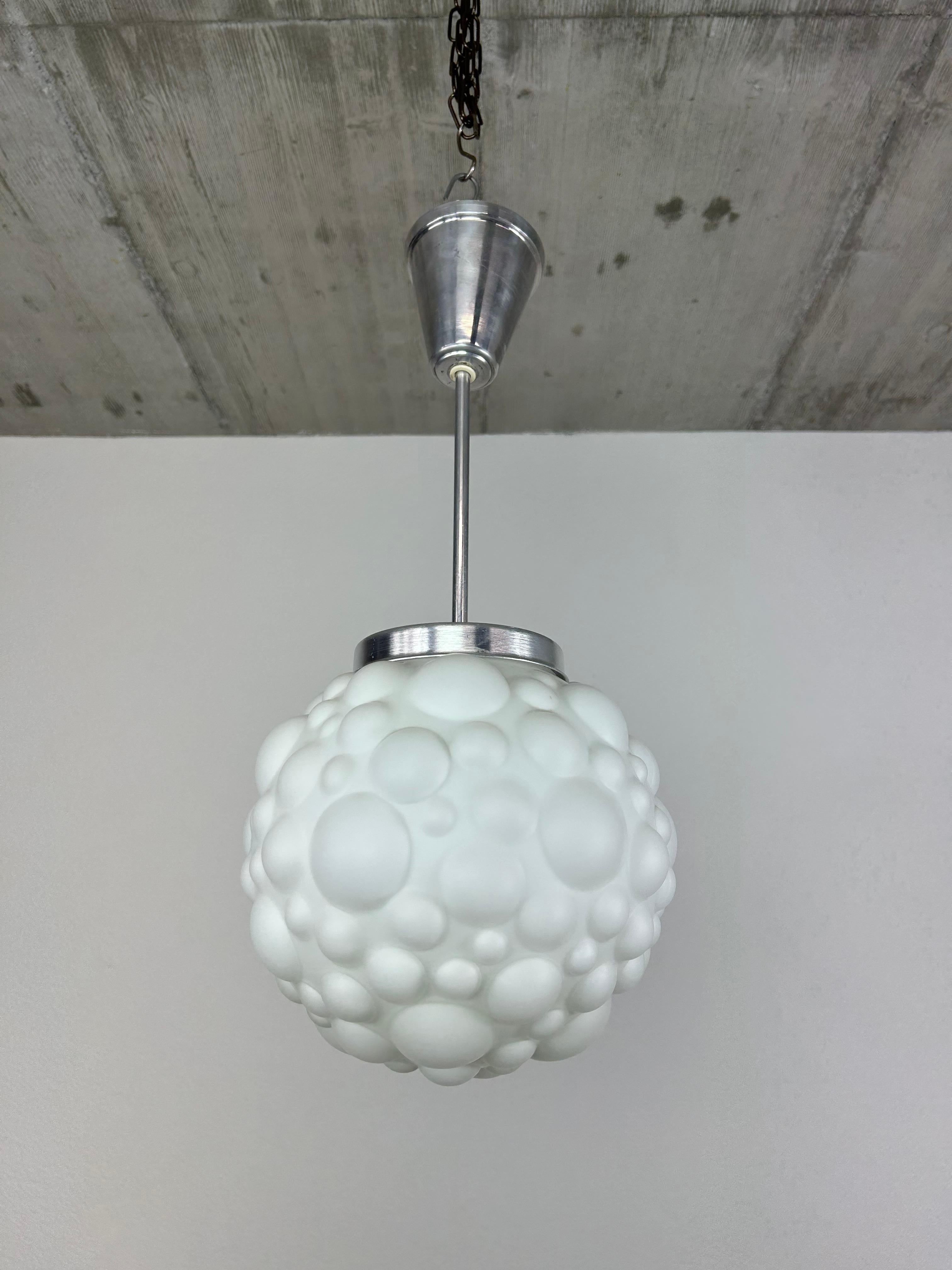 Lampada a sospensione modernista di colore bianco con paralume in vetro opalino.

