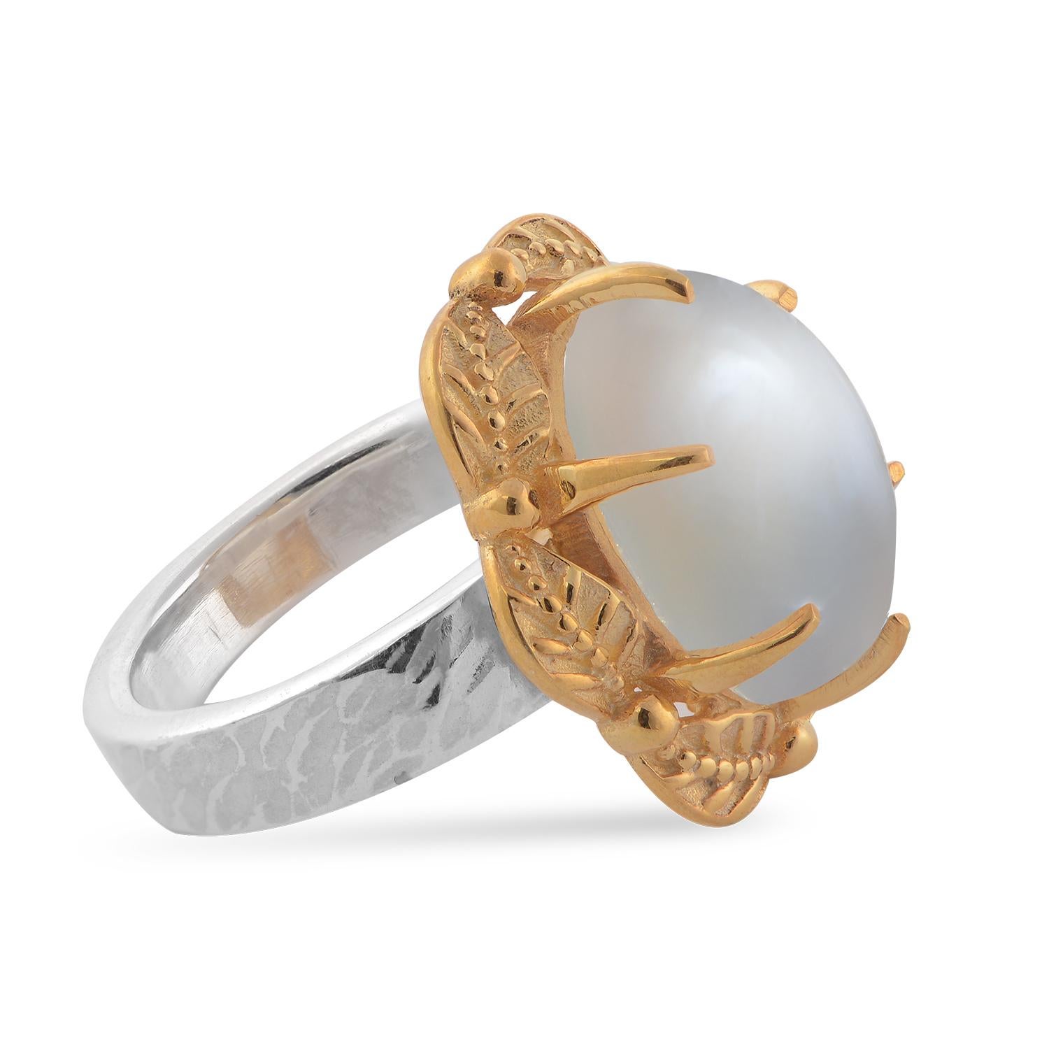 

This lovely ring has been handmade in our workshops. It is embedded with a white moonstone which is set in exquisite hand-engraved floral motifs The ring is made in sterling silver with a lightly hammered shank and the top of the ring is coated in