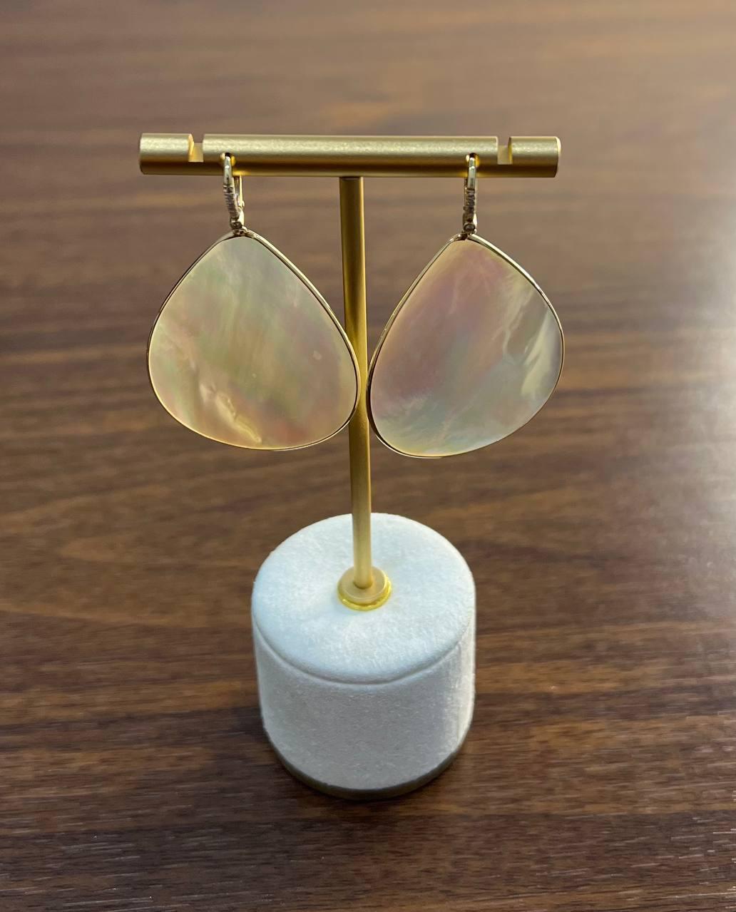 These exquisite earrings, crafted with precision and artistry.
These earrings feature a delicate teardrop design, showcasing the natural beauty of the materials. The iridescent surface reflects a spectrum of soft hues, creating a captivating play of