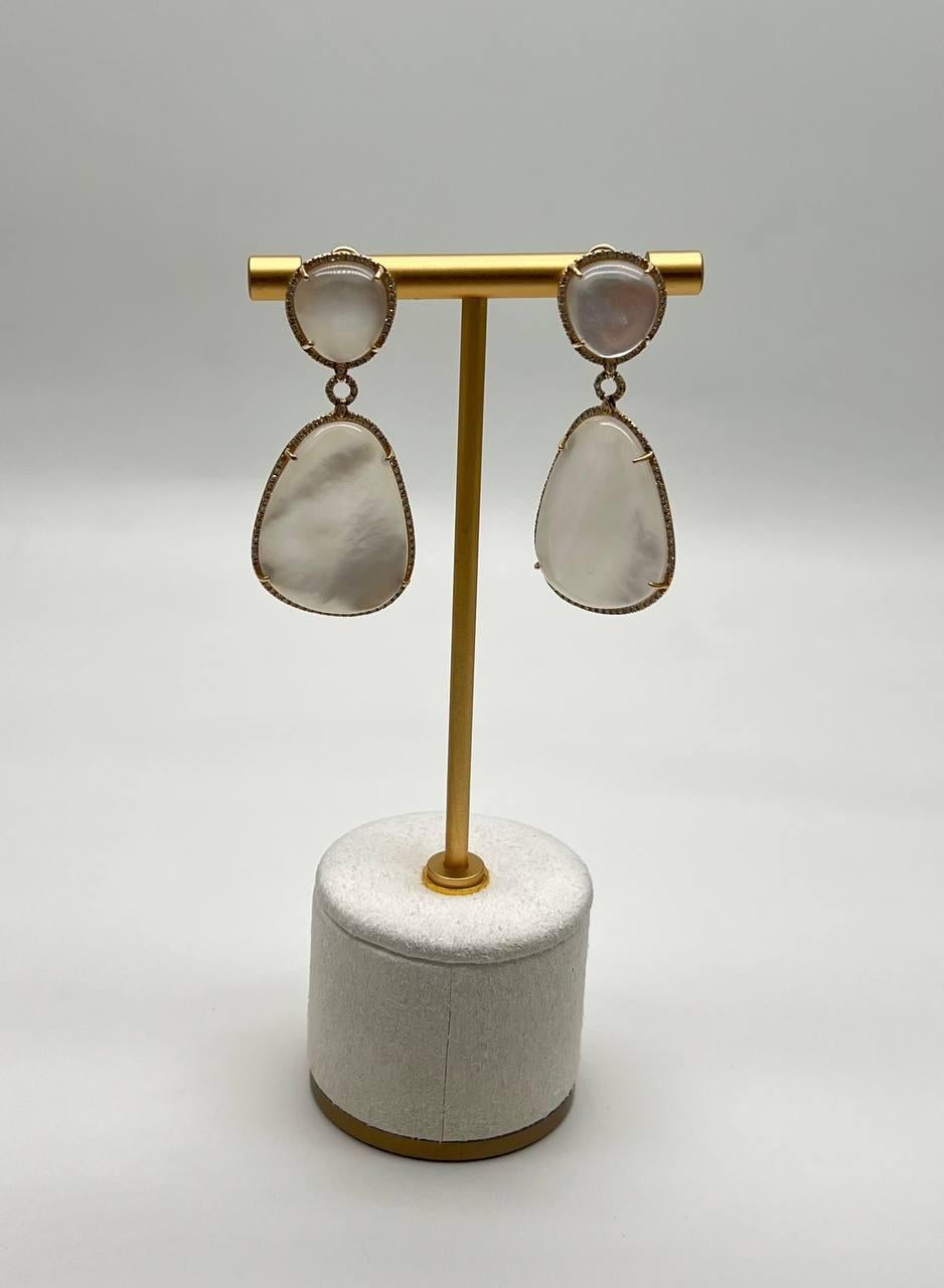 These earrings feature translucent, free form shaped white milky mother of pearl set in 14k yellow gold. The top stones are oval, while the larger bottom stones are teardrop-shaped. 14K Yellow Gold. White Diamond Halos.