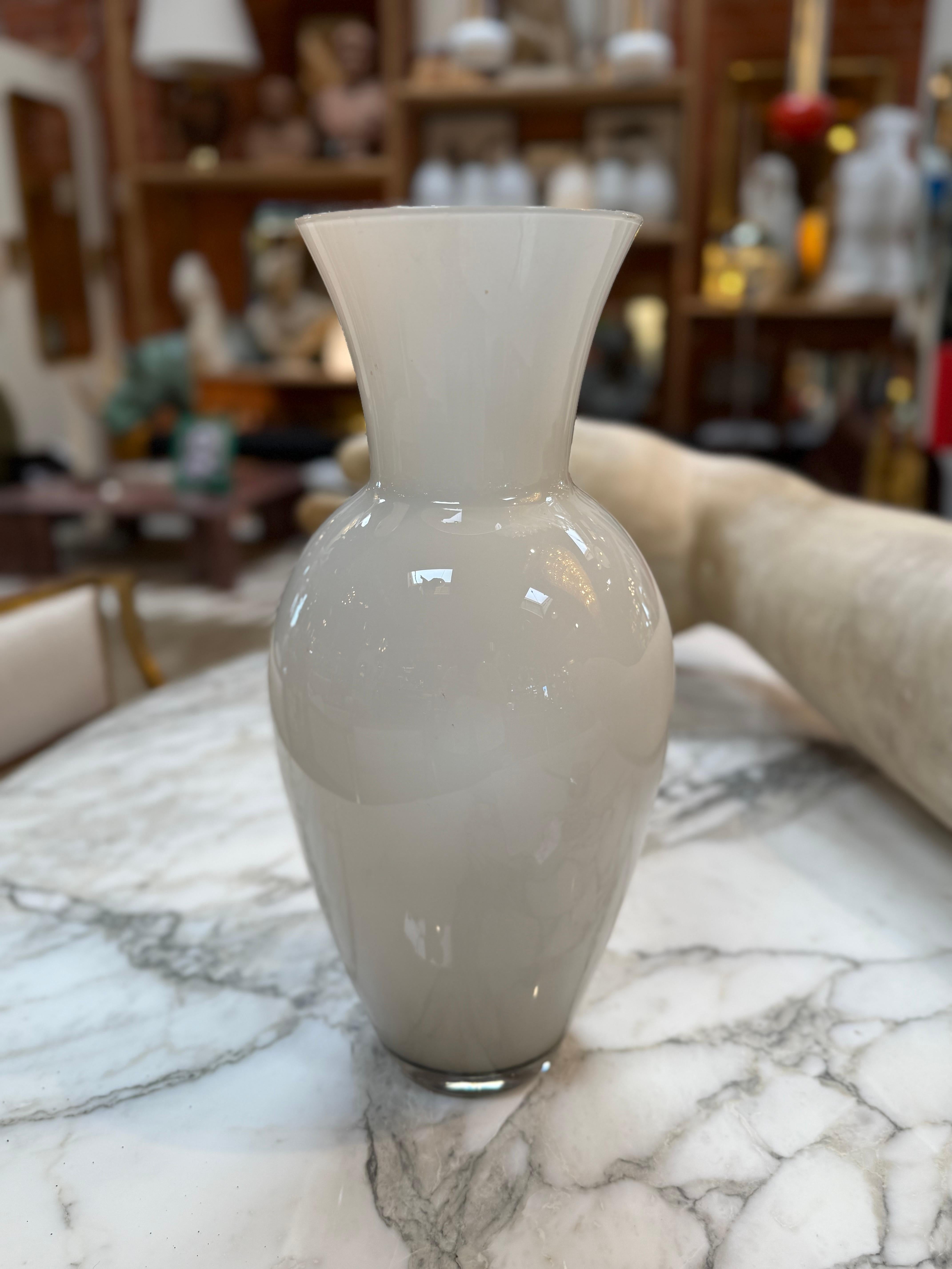 Elegante Vase aus Murano-Kunstglas in zartem, opakem Weiß, in klassischer Amphora-Form mit abgerundetem Körper und breitem, ausgestelltem Rand. Dieses von venezianischen Kunsthandwerkern mundgeblasene Stück hebt die raffinierte Handwerkskunst und