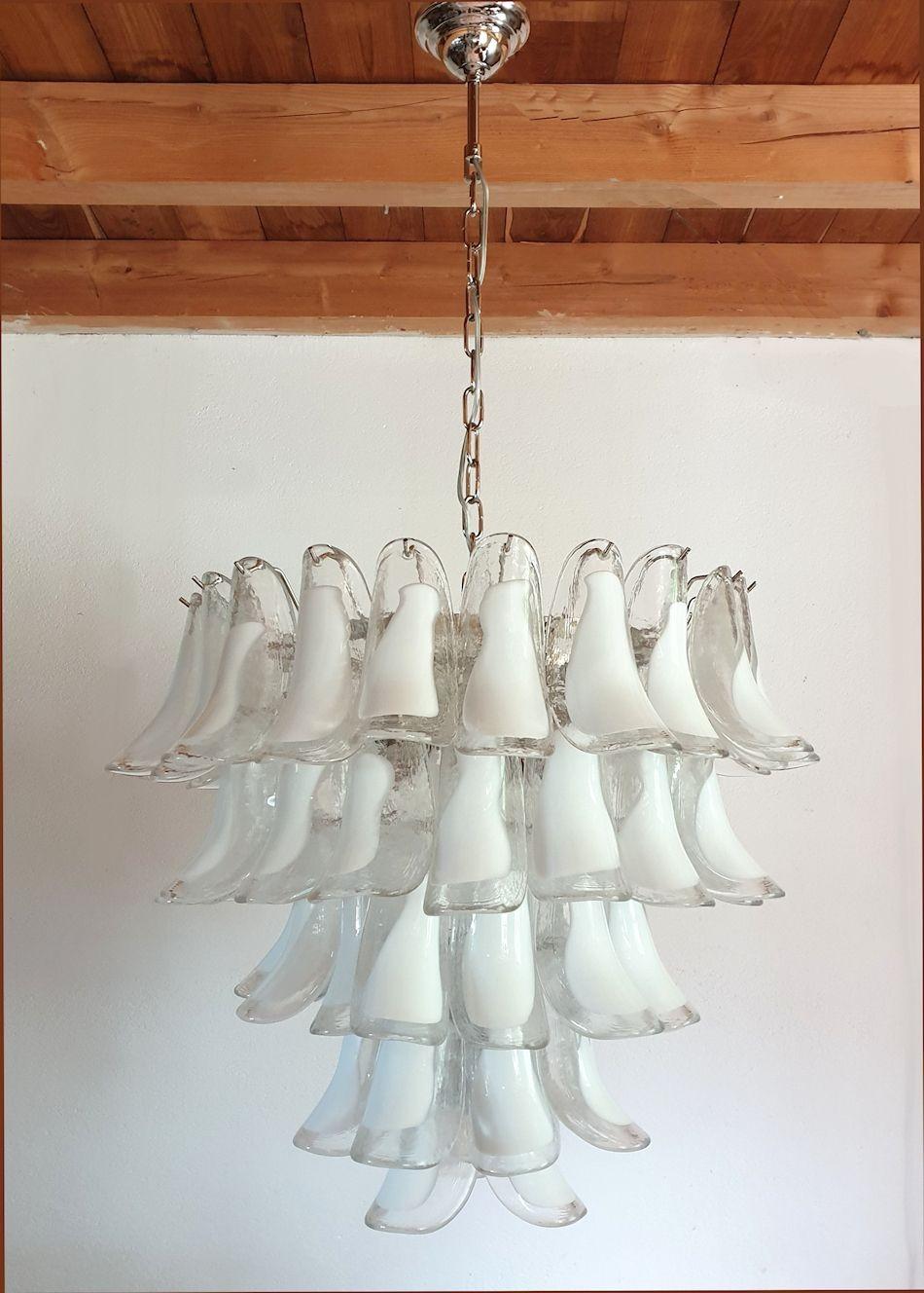 Large Mid Century Modern white Murano glass petal chandelier, by Mazzega, Italy 1980s.
A pair available - sold and priced individually.
The five-tier chandelier is made of a chrome frame and white and clear Murano glass petals.
It has 7 lights and