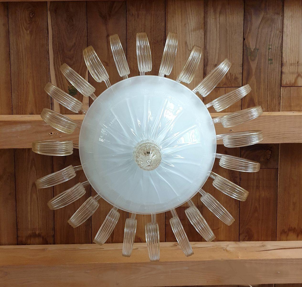 Neoklassizistischer Kronleuchter aus mundgeblasenem Murano-Glas, Venini zugeschrieben, Italien 1970er Jahre.
Dieser wunderschöne, hochwertige Kronleuchter ist aus klarem Glas mit Blattgolddekor und gedrehten Blättern gefertigt. In der Mitte befindet