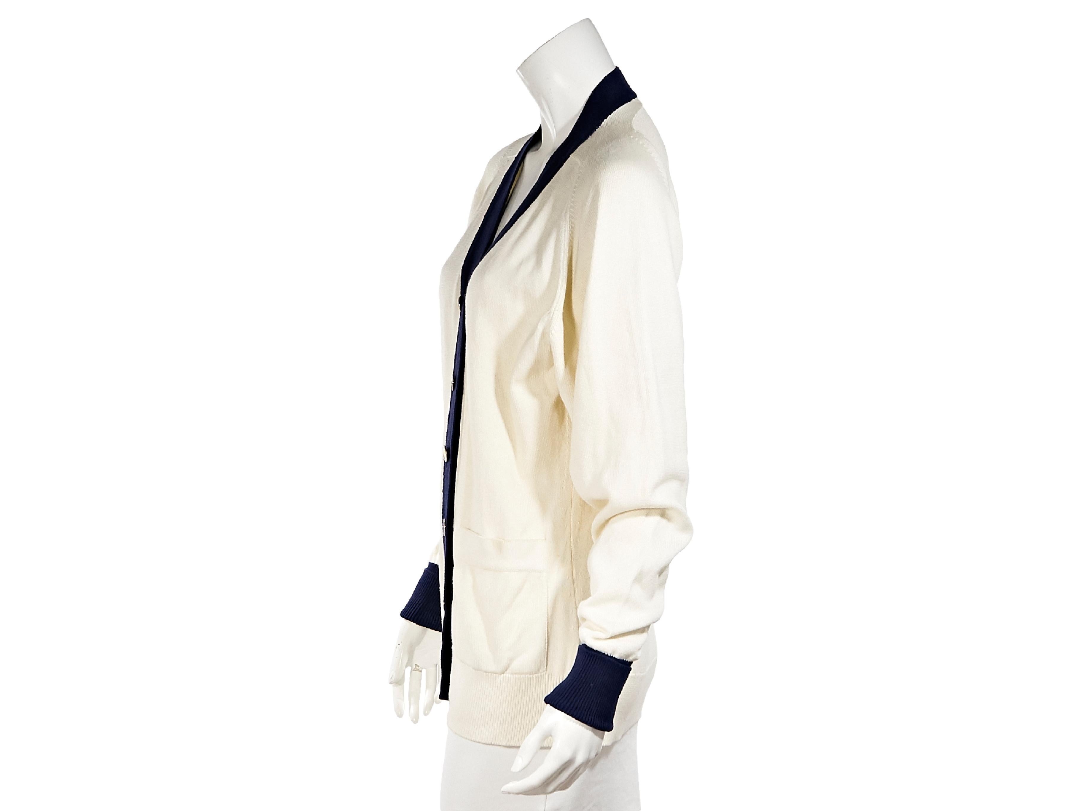 Product details:  Vintage white and navy blue cotton cardigan by Chanel.  V-neck.  Long sleeves.  Button-front closure.  Waist patch pockets.  Goldtone hardware.  37