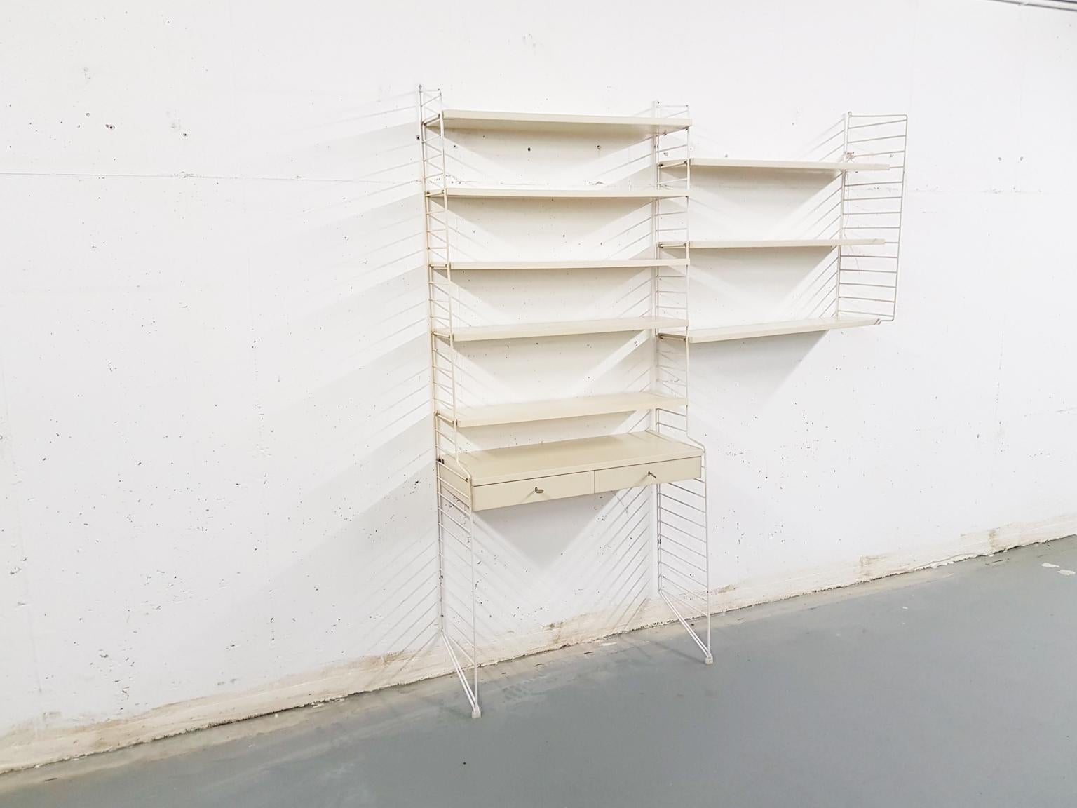 White metal risers with white veneer wooden shelves and a desk with two drawers.
The shelves and desk can be adjusted to any height.
(Sold without the stool)


Nisse Strinning
Nils 