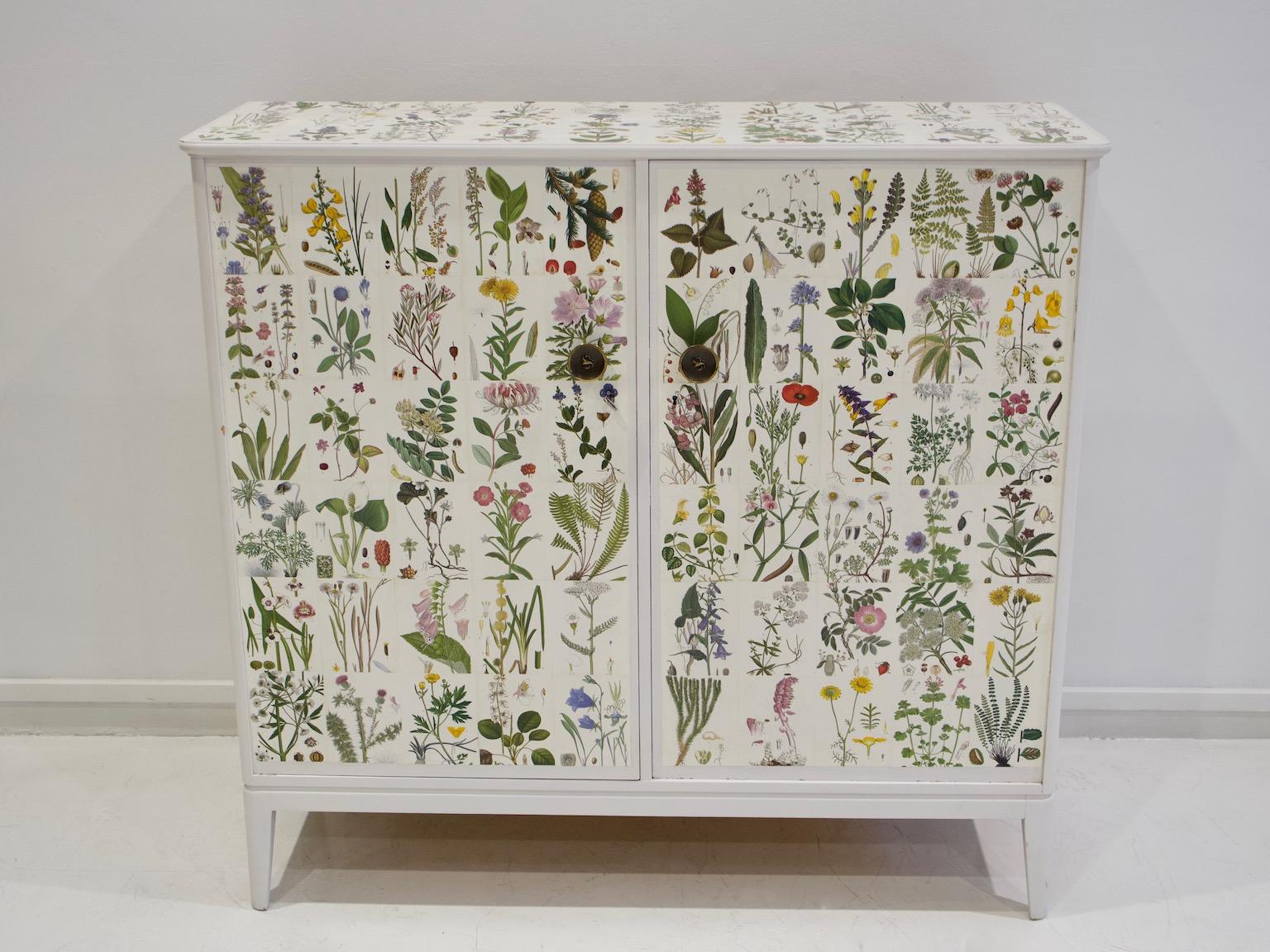 White painted wooden cabinet decorated with illustrations from the book 