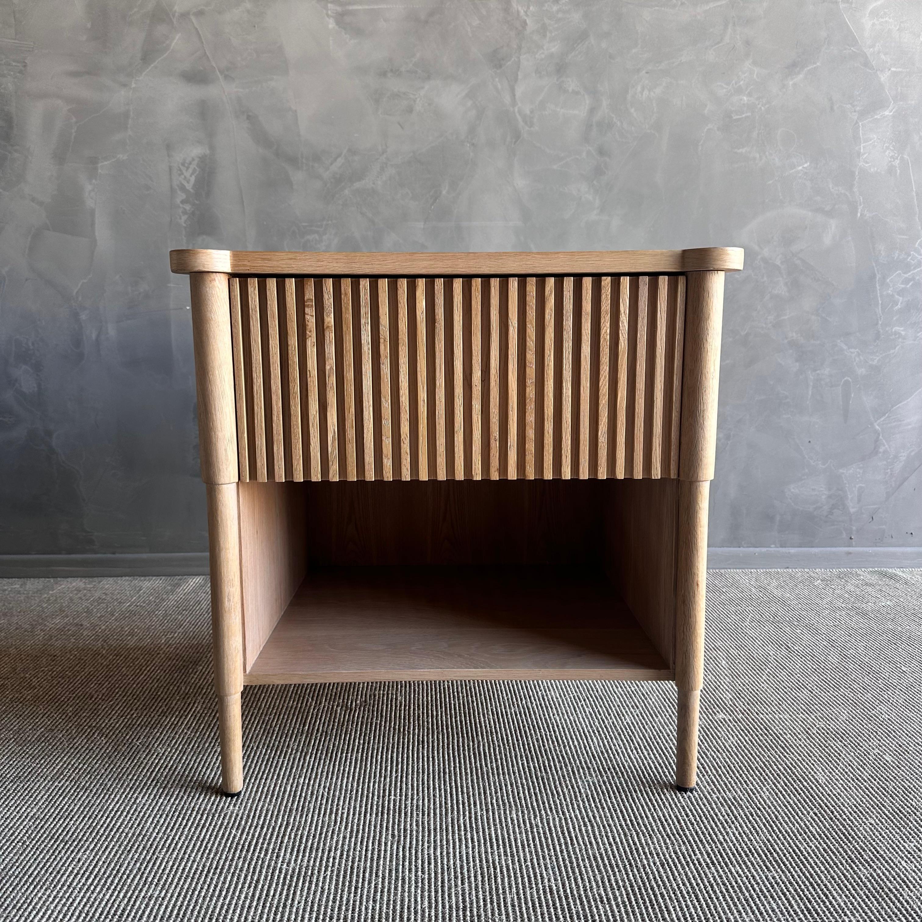 Introducing the Reed White Oak Nightstand, a timeless piece constructed from solid white oak with a natural finish. The reeded drawer front and sides add a touch of elegance and sophistication to any bedroom decor. Quality made, this nightstand