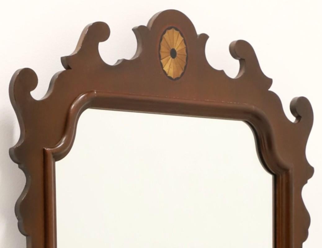 A Chippendale style dressing mirror by White Furniture. Mirrored glass, portrait oriented, decoratively carved mahogany frame with inlaid medallion to the top and a banded drawer base. Features one felt-lined drawer of dovetail construction with a