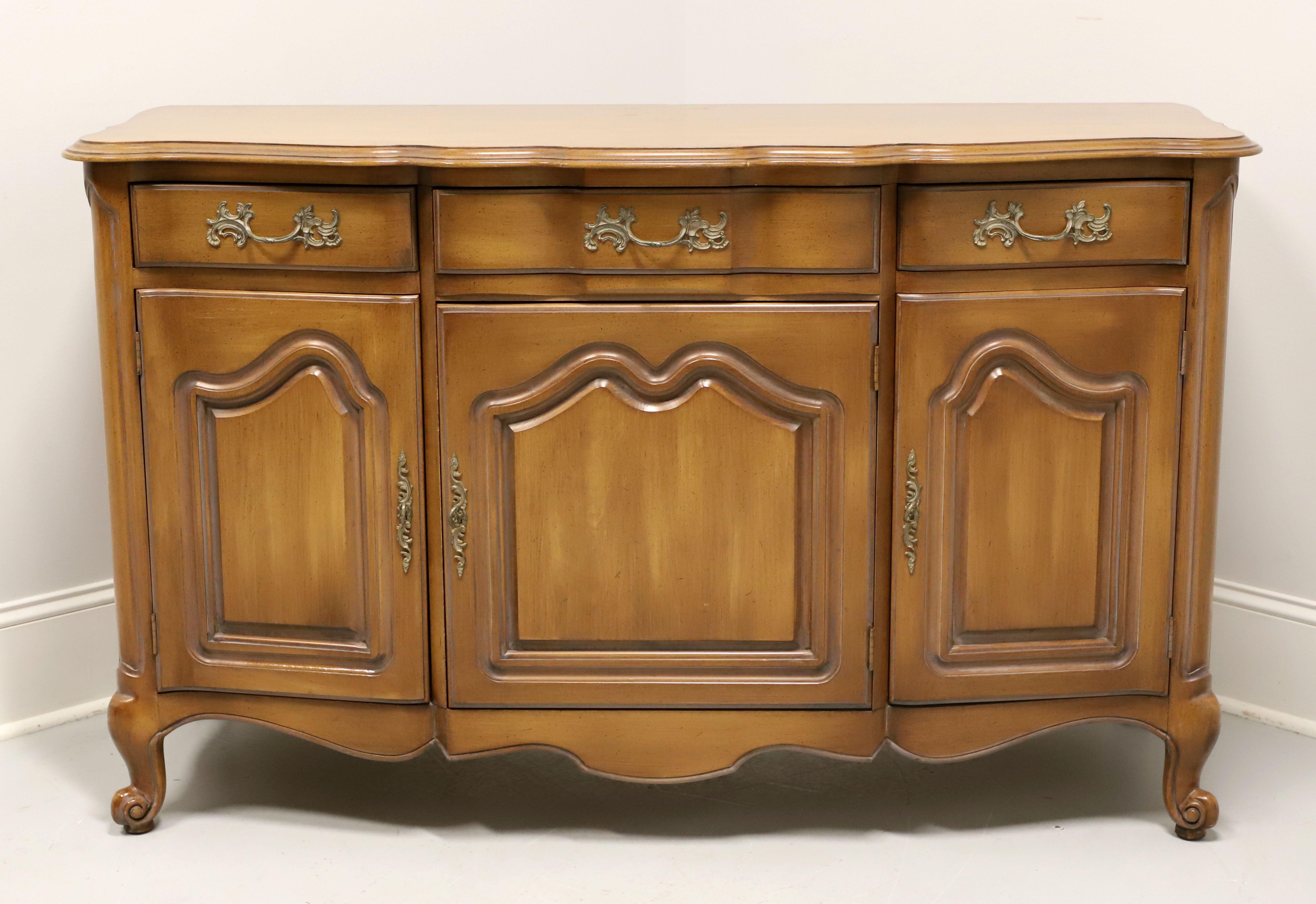 A French Provincial Louis XV style credenza by White Furniture. Solid cherry wood with their Old Spice finish, ogee edge to the top, serpentine shape, brass hardware, carved door fronts, carved apron, and scroll feet. Features three drawers of