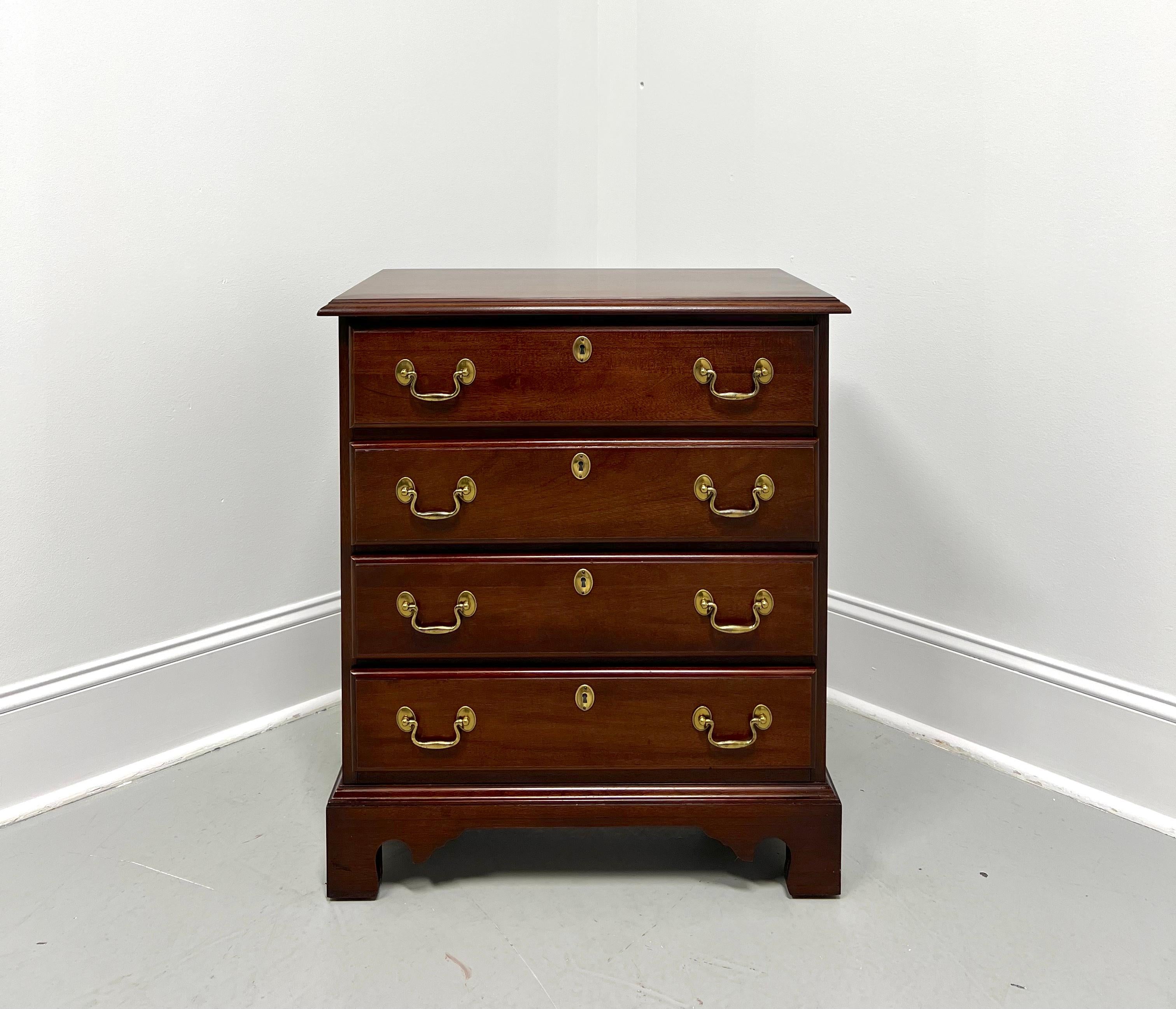 A Chippendale style bedside chest by White Furniture. Mahogany with brass hardware, ogee edge to the top, brass side handles, and bracket feet. Features four drawers of dovetail construction with faux keyhole escutcheons. Made in the USA, circa