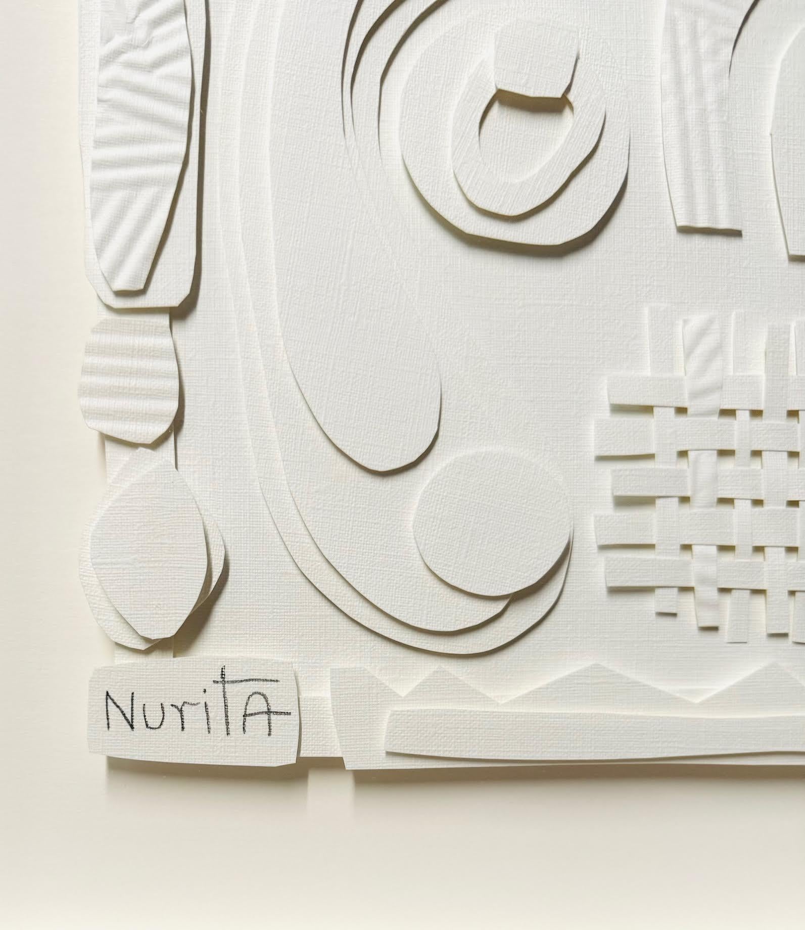Collage de recortes de papel blanco sobre blanco.
Marco cuadrado de madera blanca.
La artista Nurit Amdur crea recortes de papel y collages que giran en torno al viaje de transición y a convertir algo en 