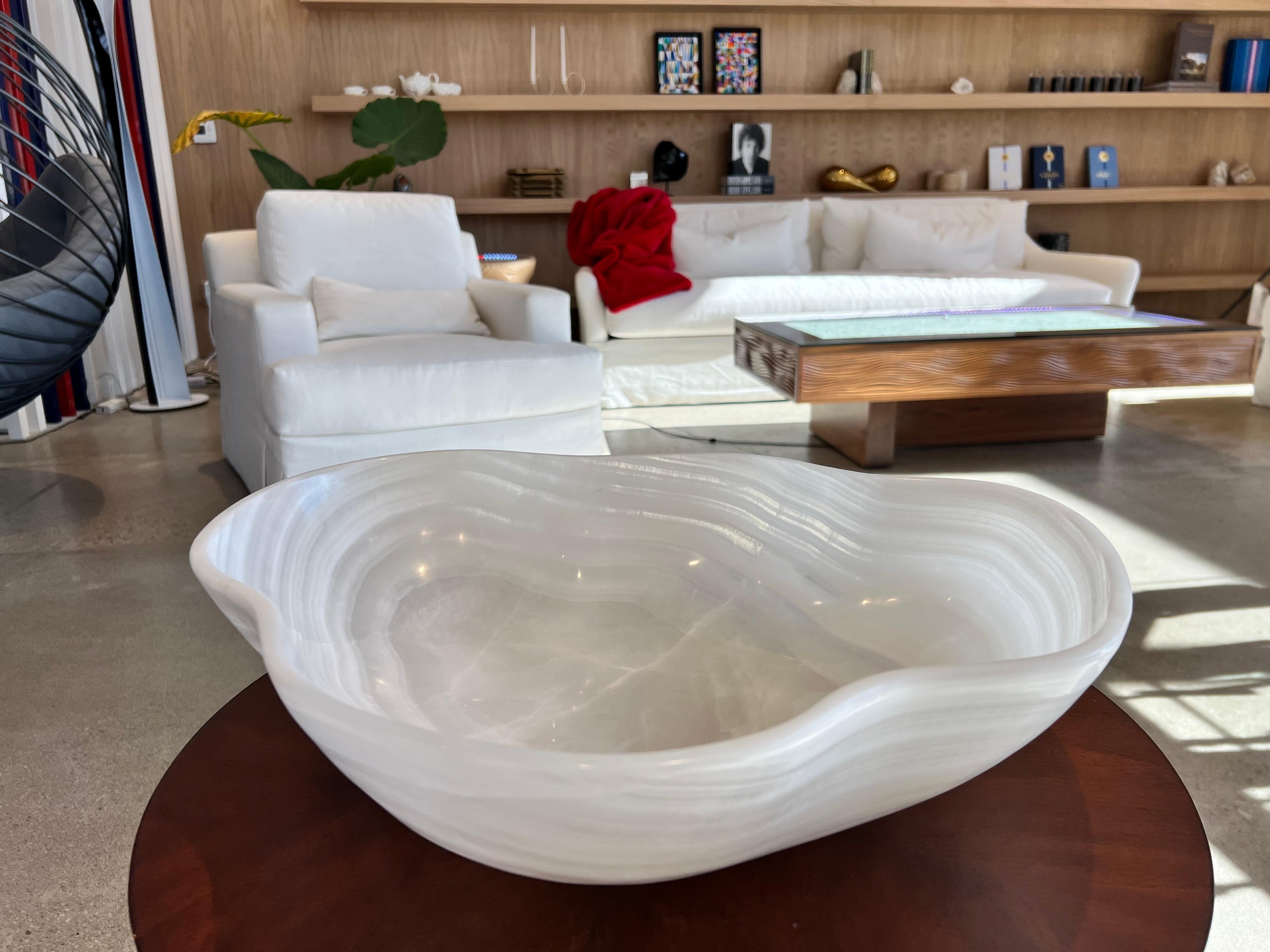 Hand-carved in Mexico from a single piece of onyx. One of a kind  A spectacular, organic, vessel of white transparent stone with natural veining and inclusions. This stunning bowl is polished inside and out, with fluted sides and a polished rim. Its